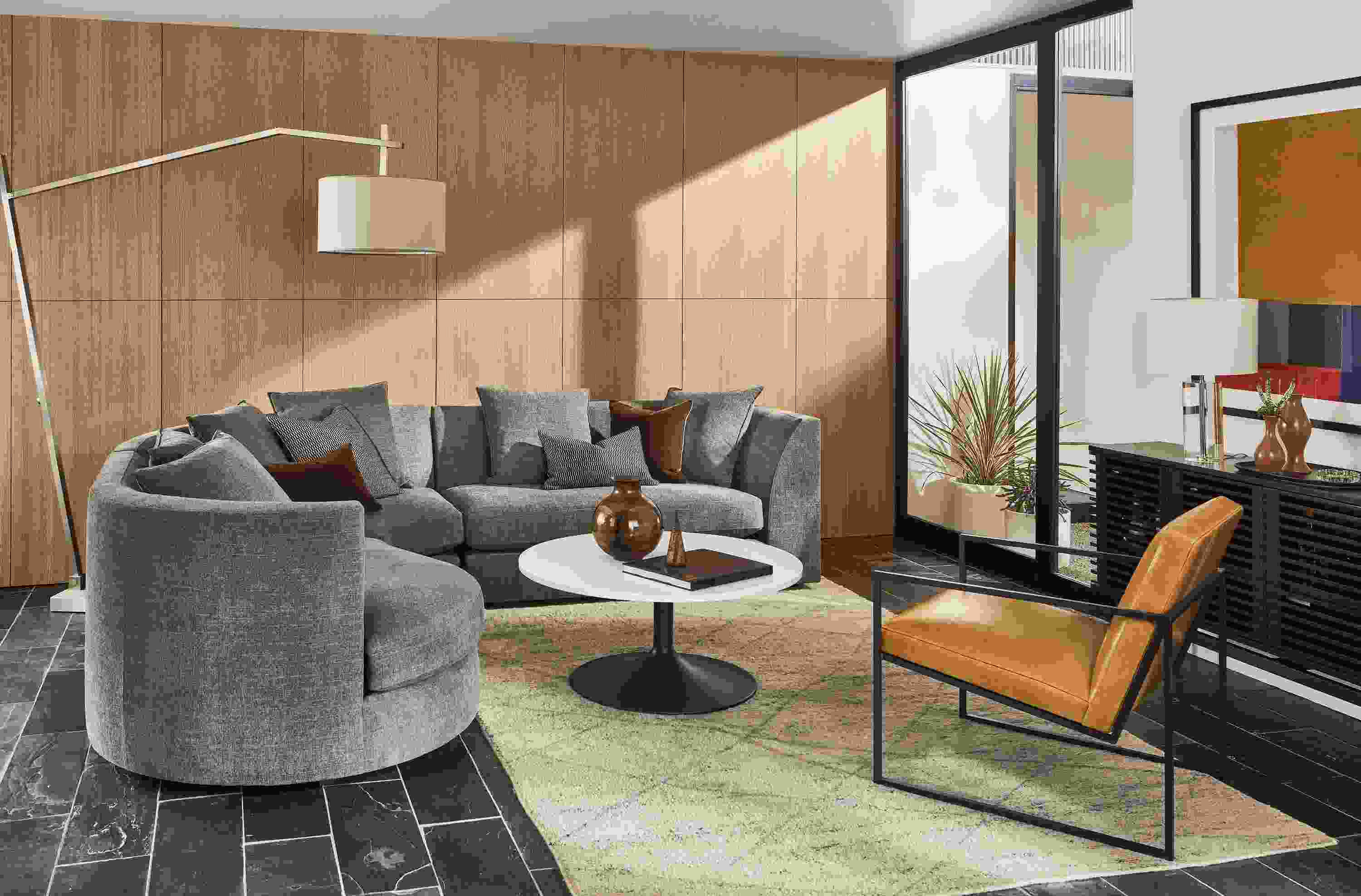 Living room with Astaire 3-piece curved sectional, Novato chair in vento camel leather, Aria coffee table and kalindi rug.