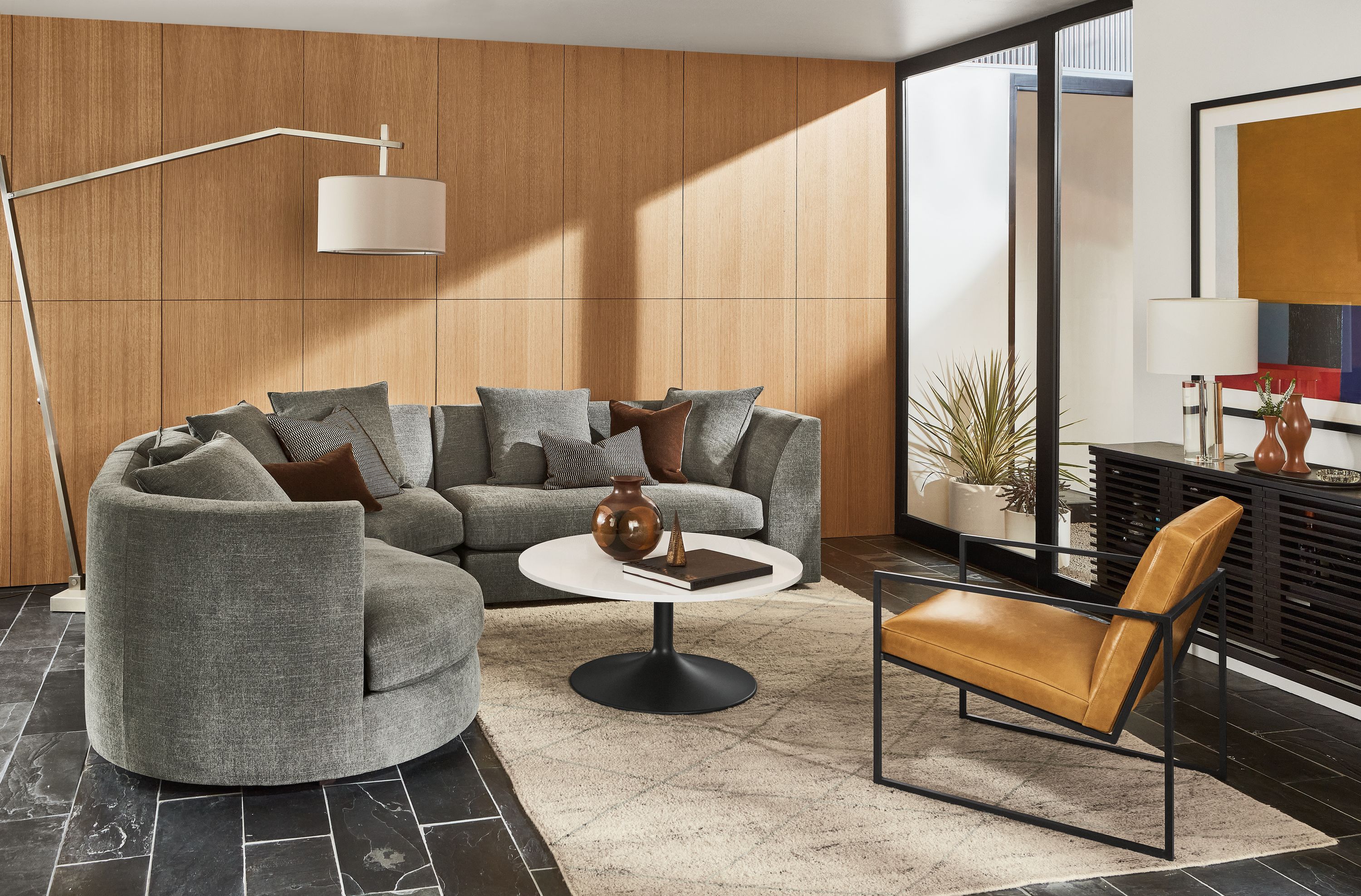 room setting including astaire 3-piece curved sectional, novato chair in vento leather, aria coffee table, kalindi rug.