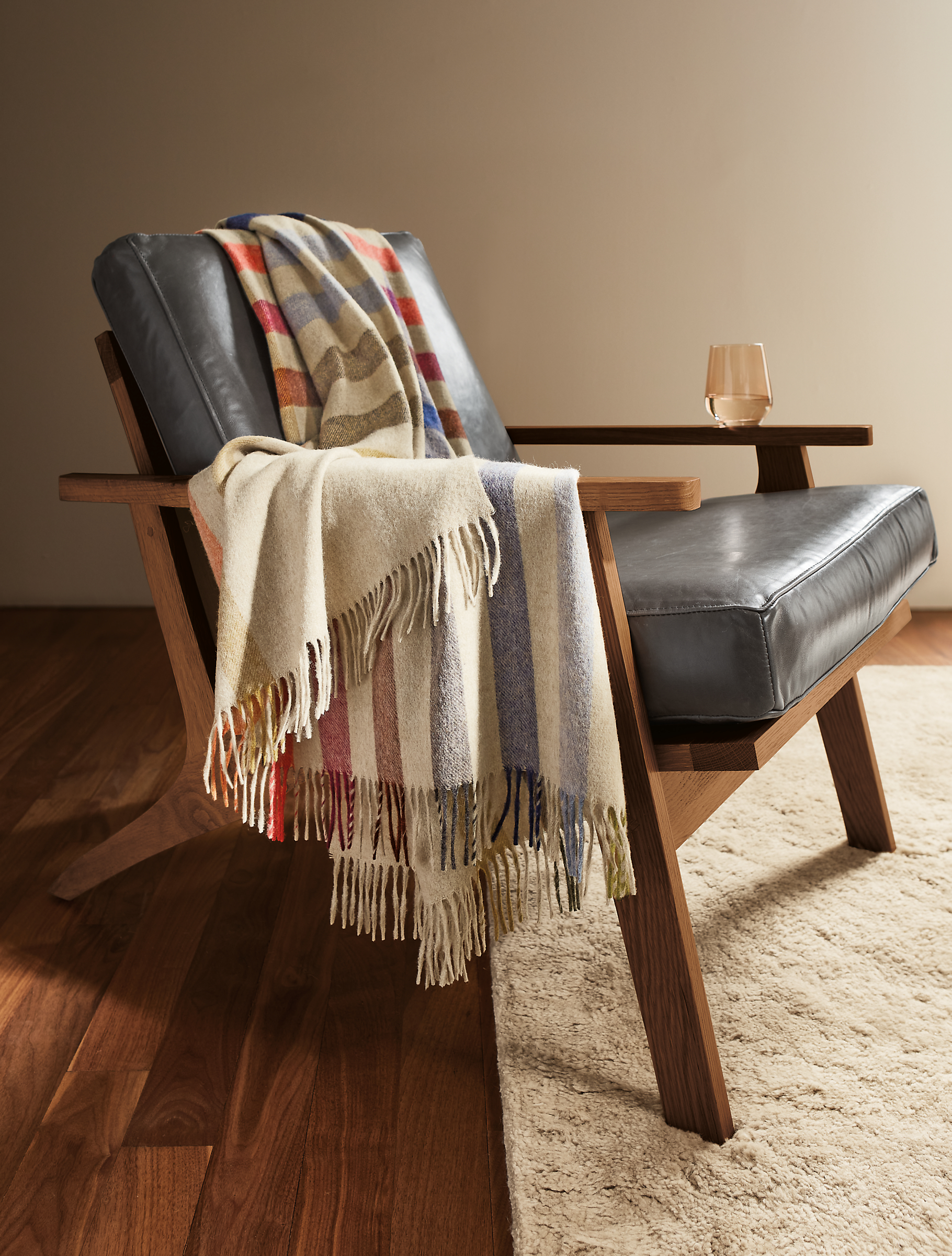 detail of audrey throw blanket draped on sanna chair in walnut and leather..