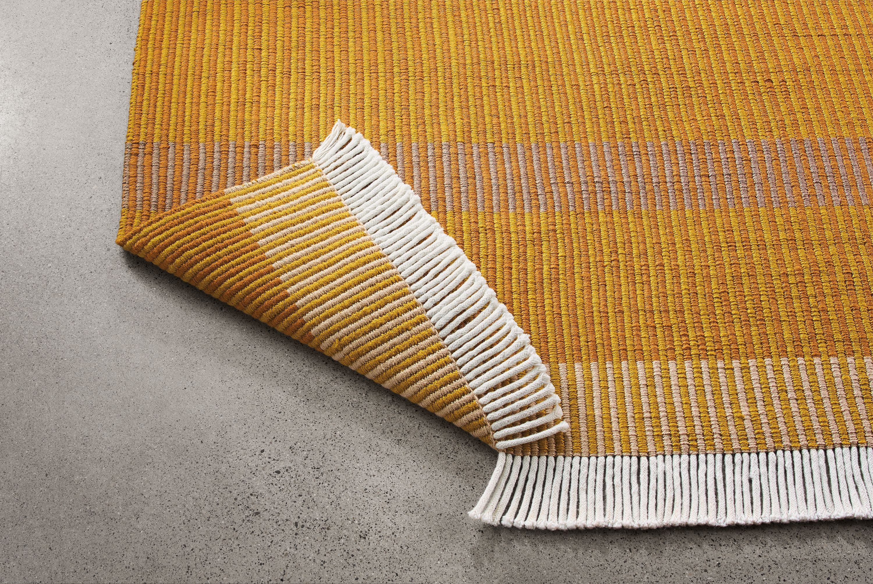 Detail of ayla 8 by 10 rug in mustard with corner turned up to show underside of rug.