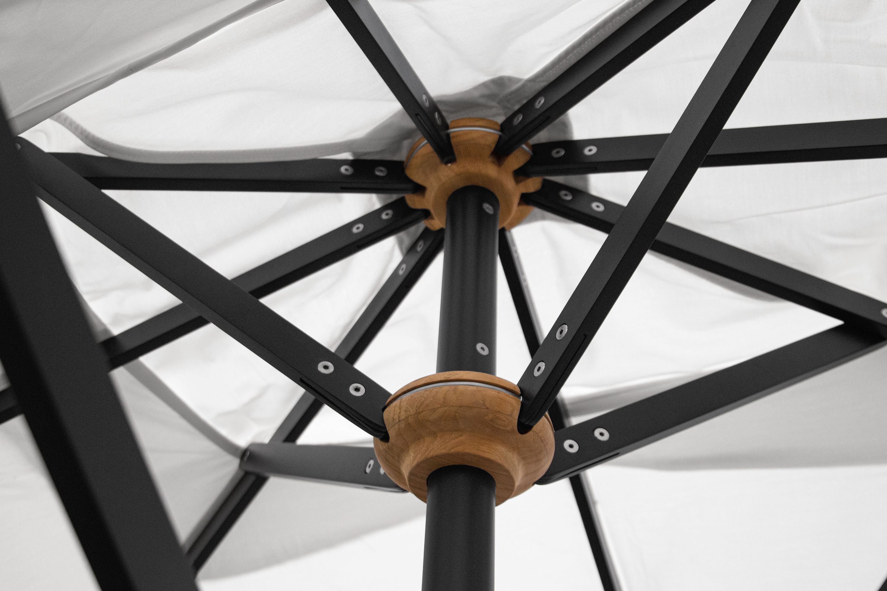 Detail of the rib assembly on a Banda 12 by 8 telescopic patio umbrella with black base in halo white.