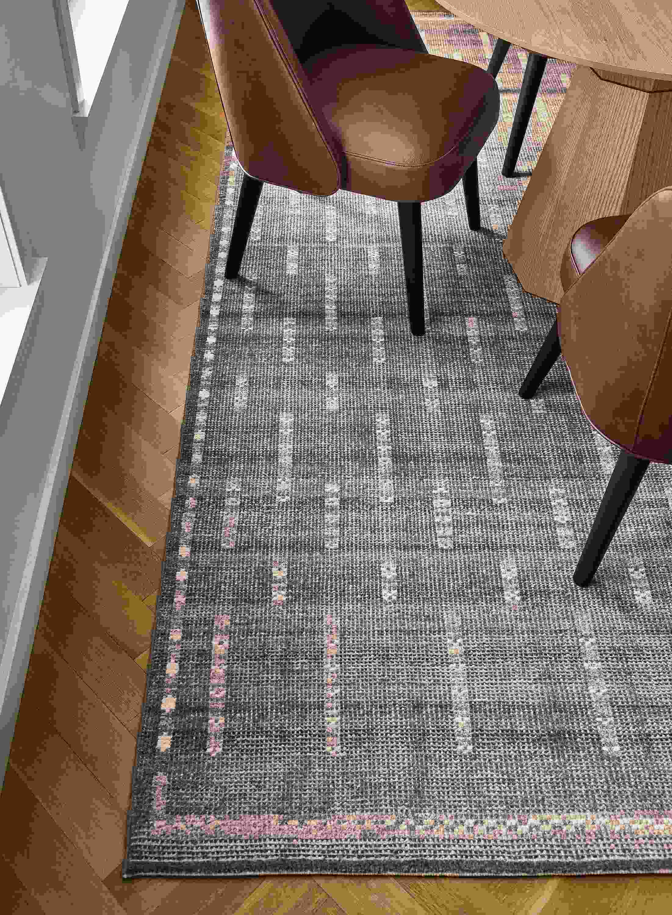 Detail of baran 8 by 10 rug in grey, glover round table in rye on red oak and cora side chair in laino cognac and charcoal legs.
