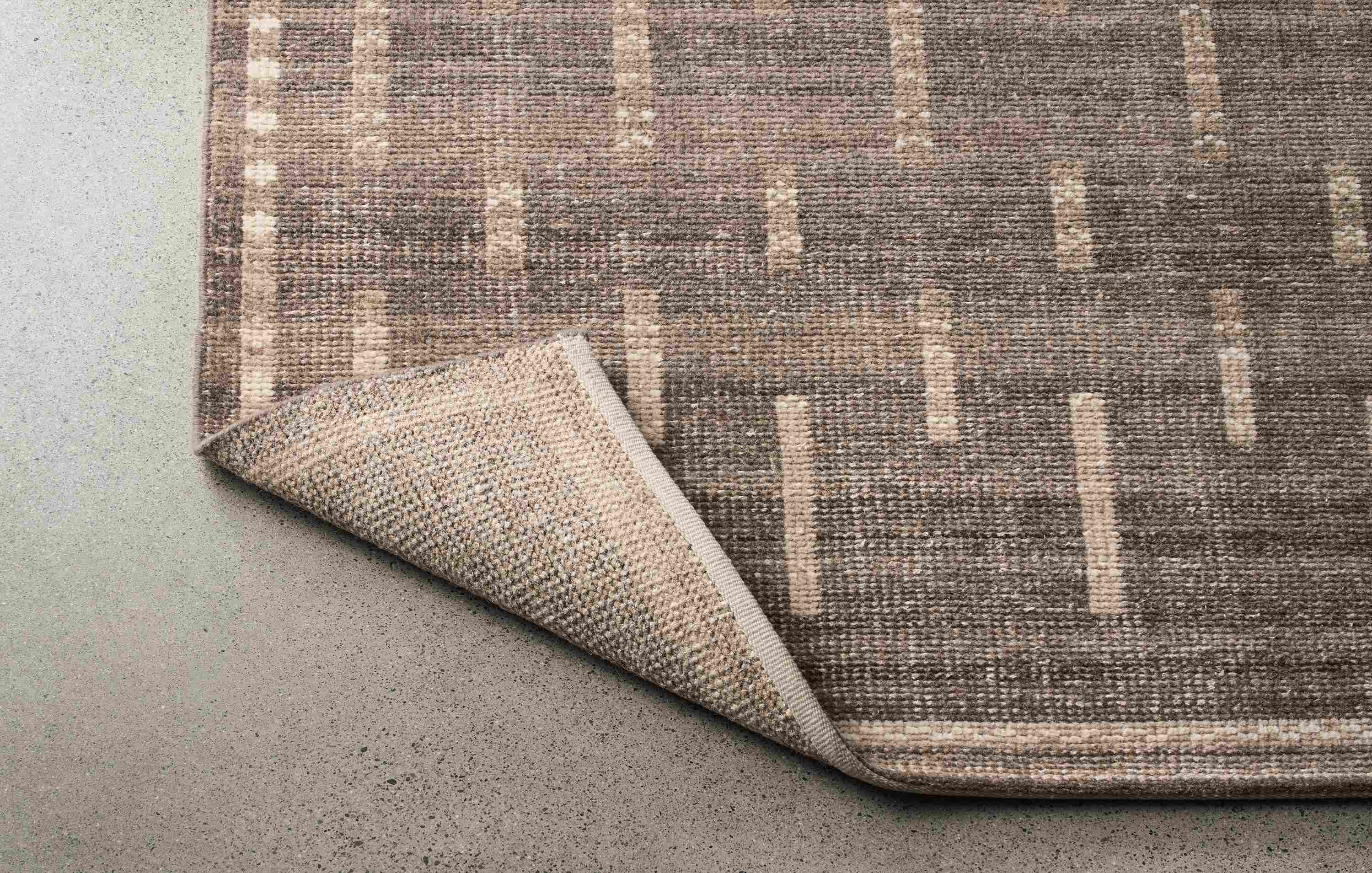 Baran 8 by 10 rug in grey shown with corner turned over to show the underside of rug.