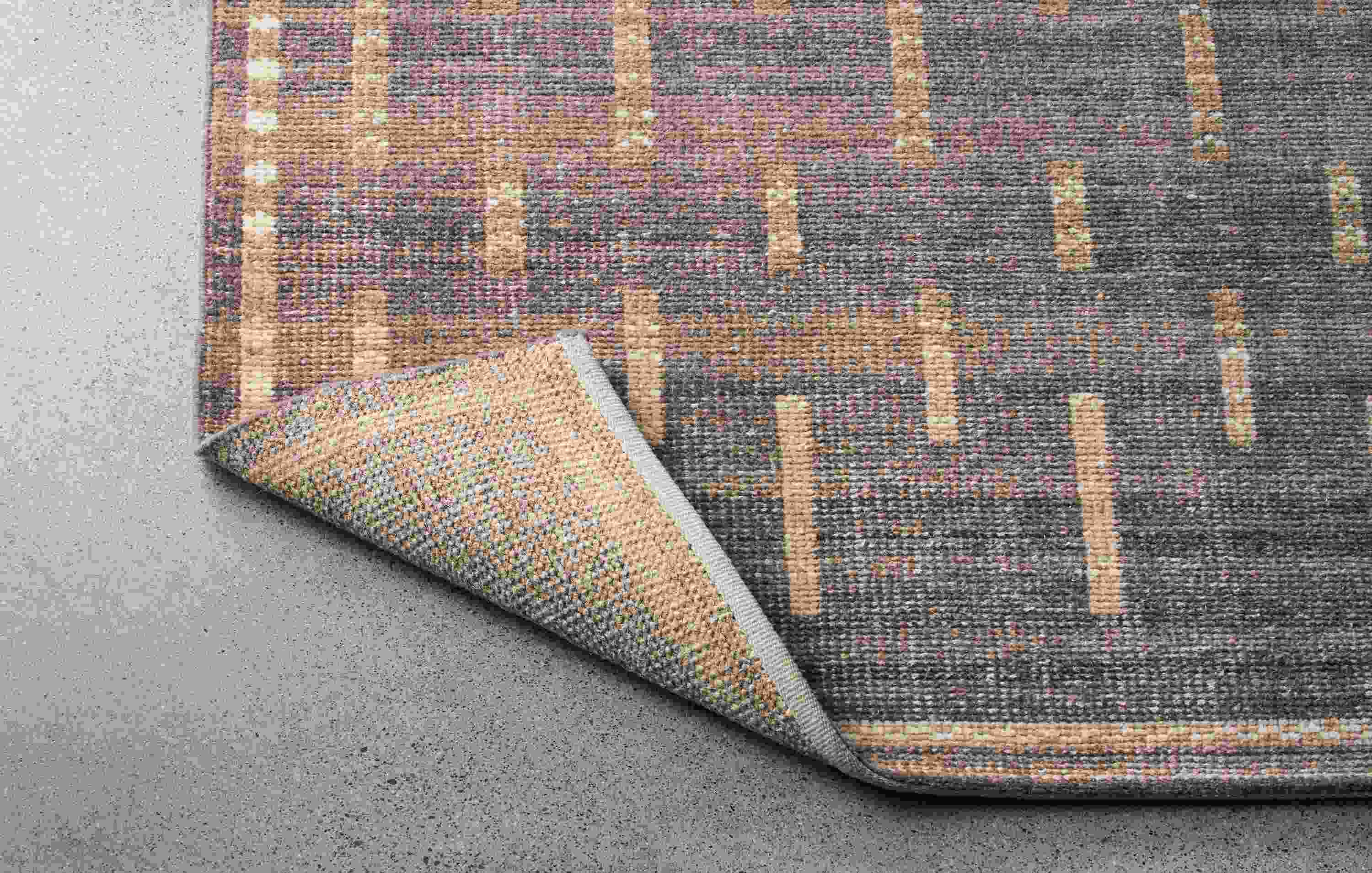 Baran 8 by 10 rug in grey shown with corner turned over to show the underside of rug.