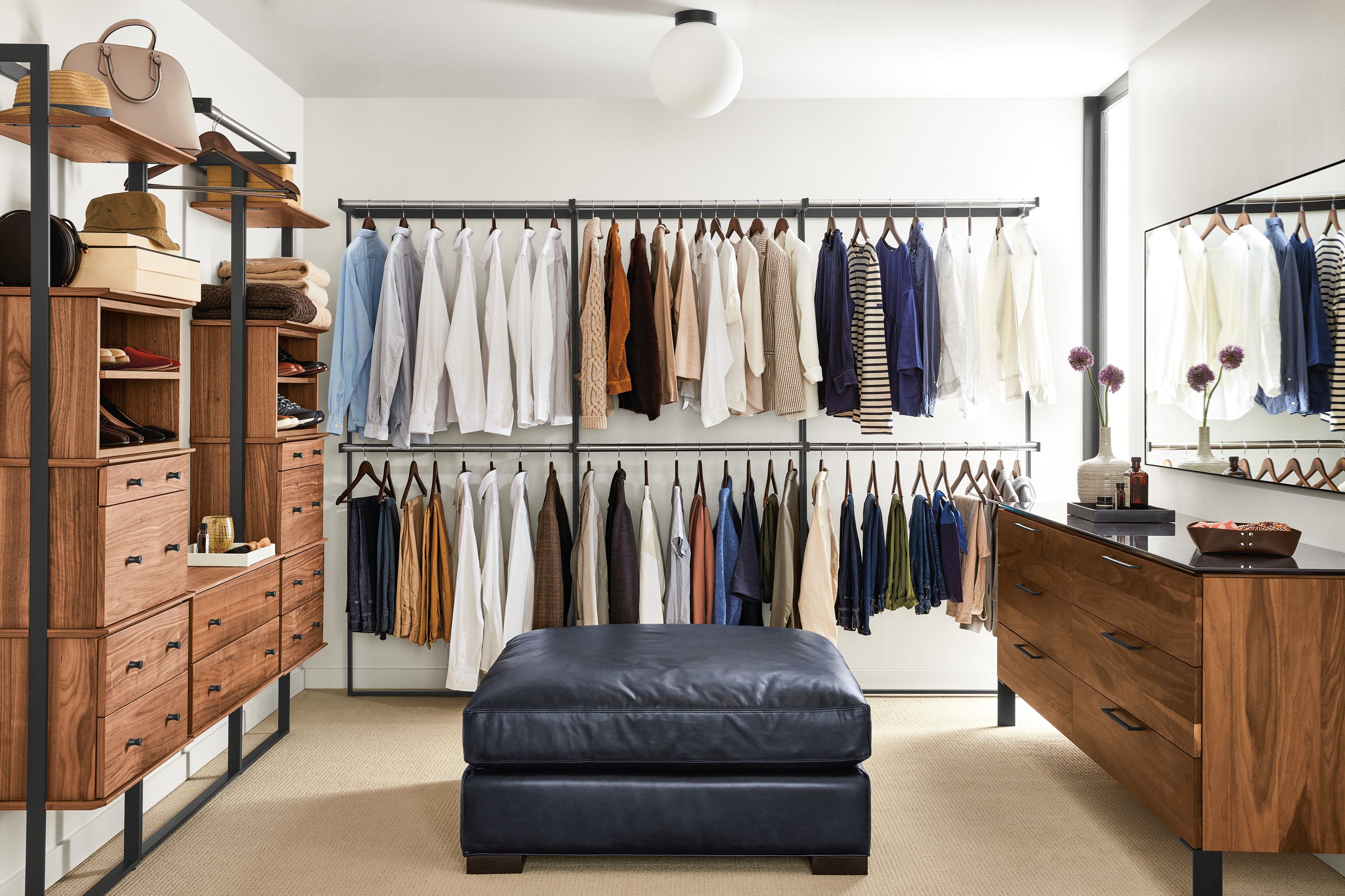 Large closet with multiple Beam bookcases with inserts and hanging closet racks in walnut and graphite, Kenwood dresser in walnut and metro ottoman.