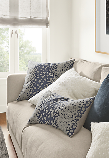 Detail of 4 Bella throw pillows in white and indigo on sofa.