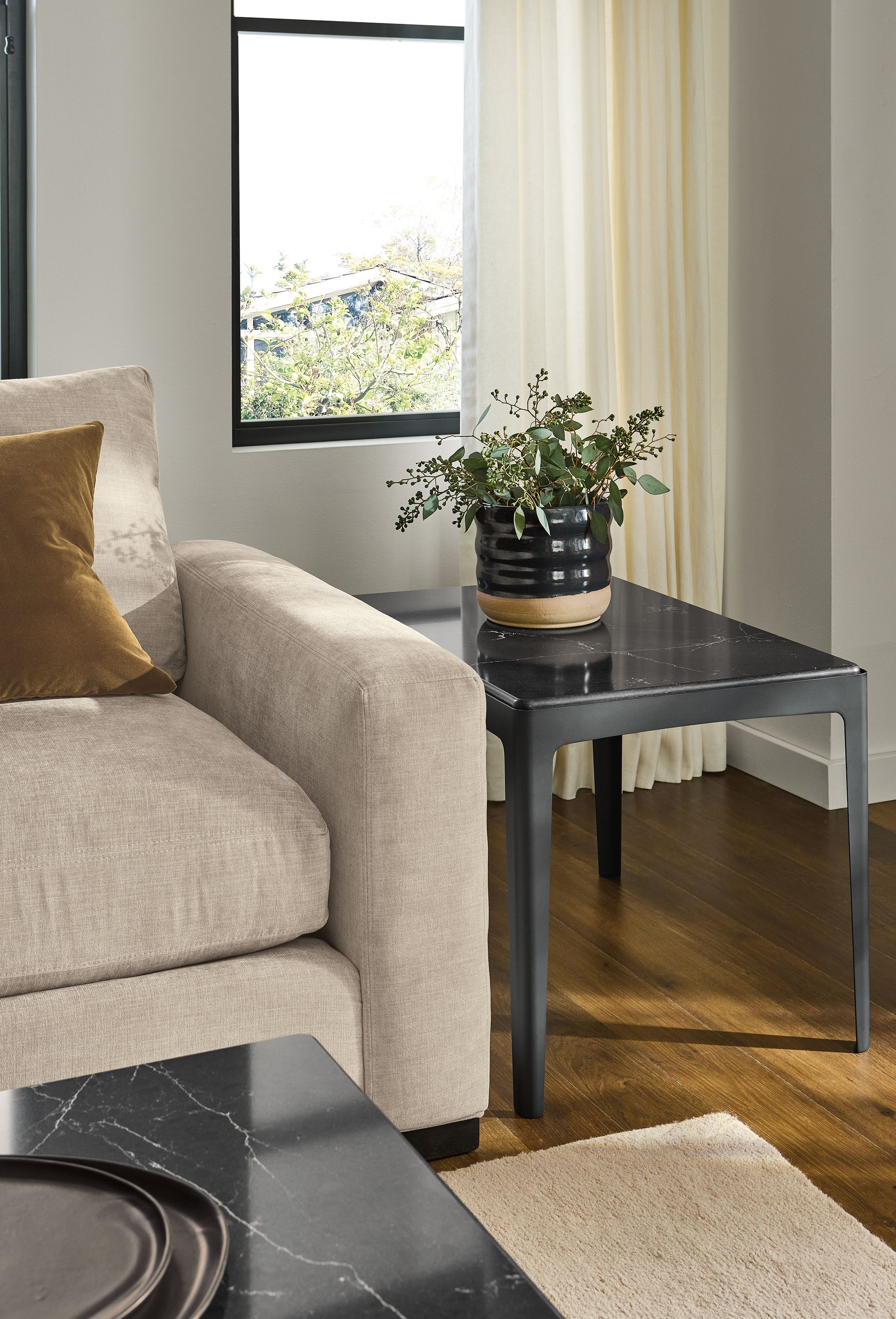 Living room with Belmar end table and coffee table in graphite and Marbled Black Quartz and a Metro sofa in Mori Oatmeal.