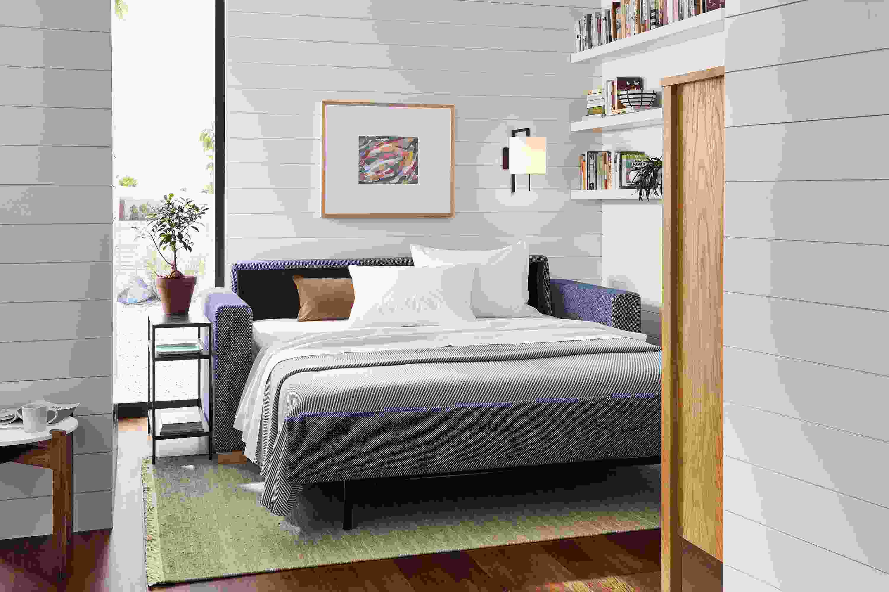 Small living space with Berin 82-wide sleeper sofa in Arin Navy in open position with slim end table.