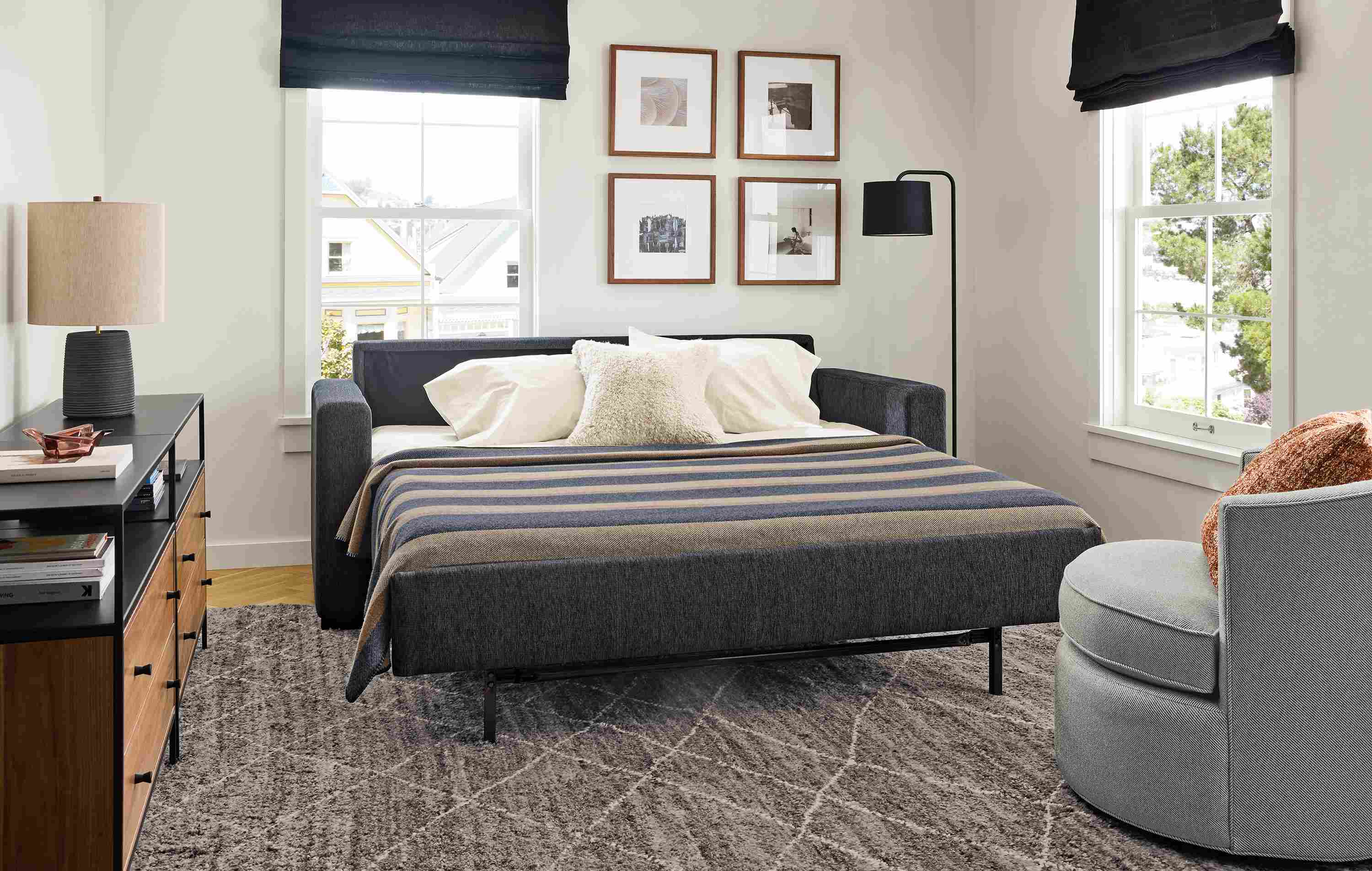 Living room with Berin queen sleeper sofa in crawford navy shown with sleeper bed open and Kalindi rug in charcoal.