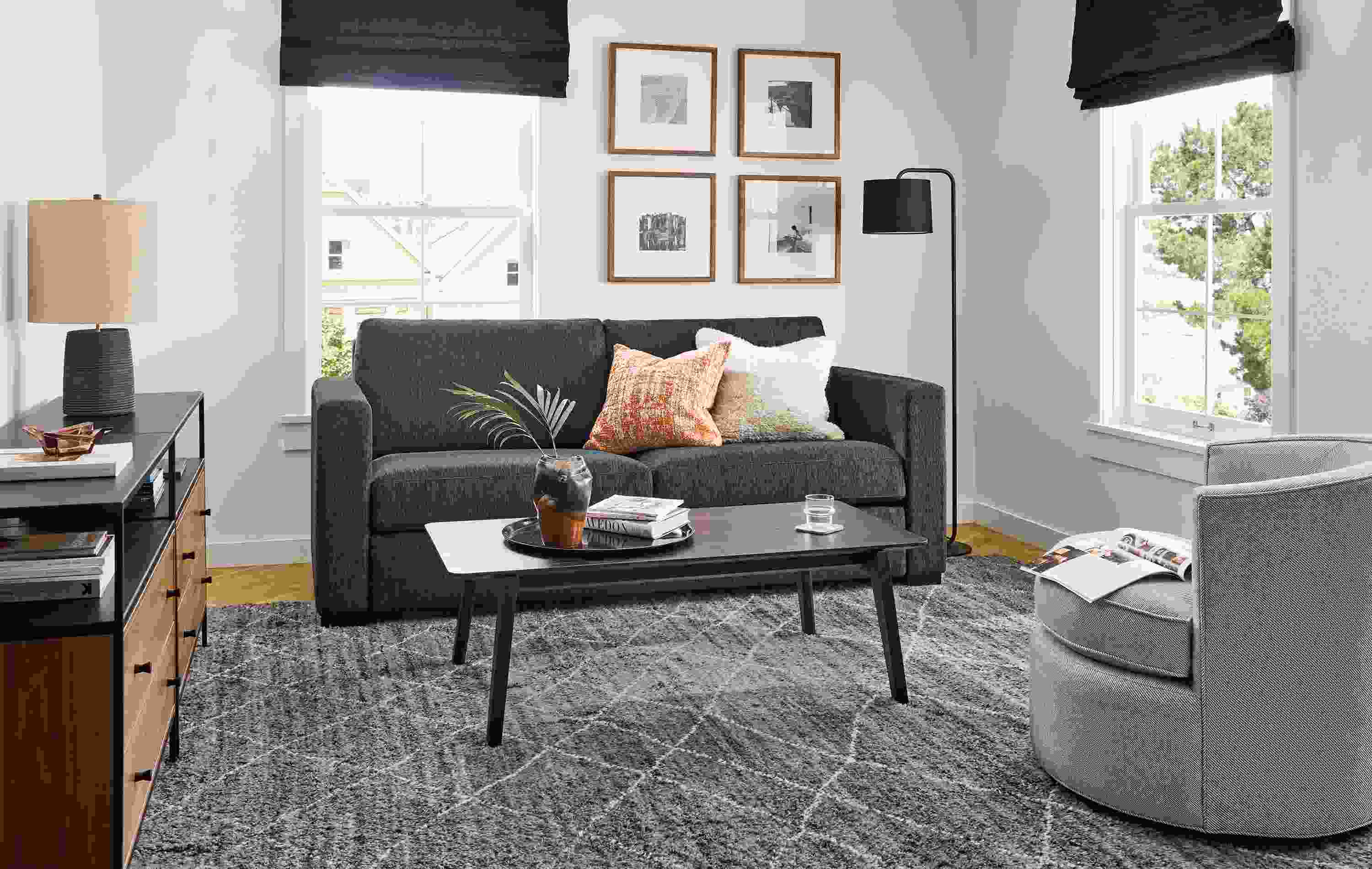 Living room with Berin 82-wide queen-plus sleeper sofa in crawford navy, Otis swivel chair in Derry Cement and Orlin table.