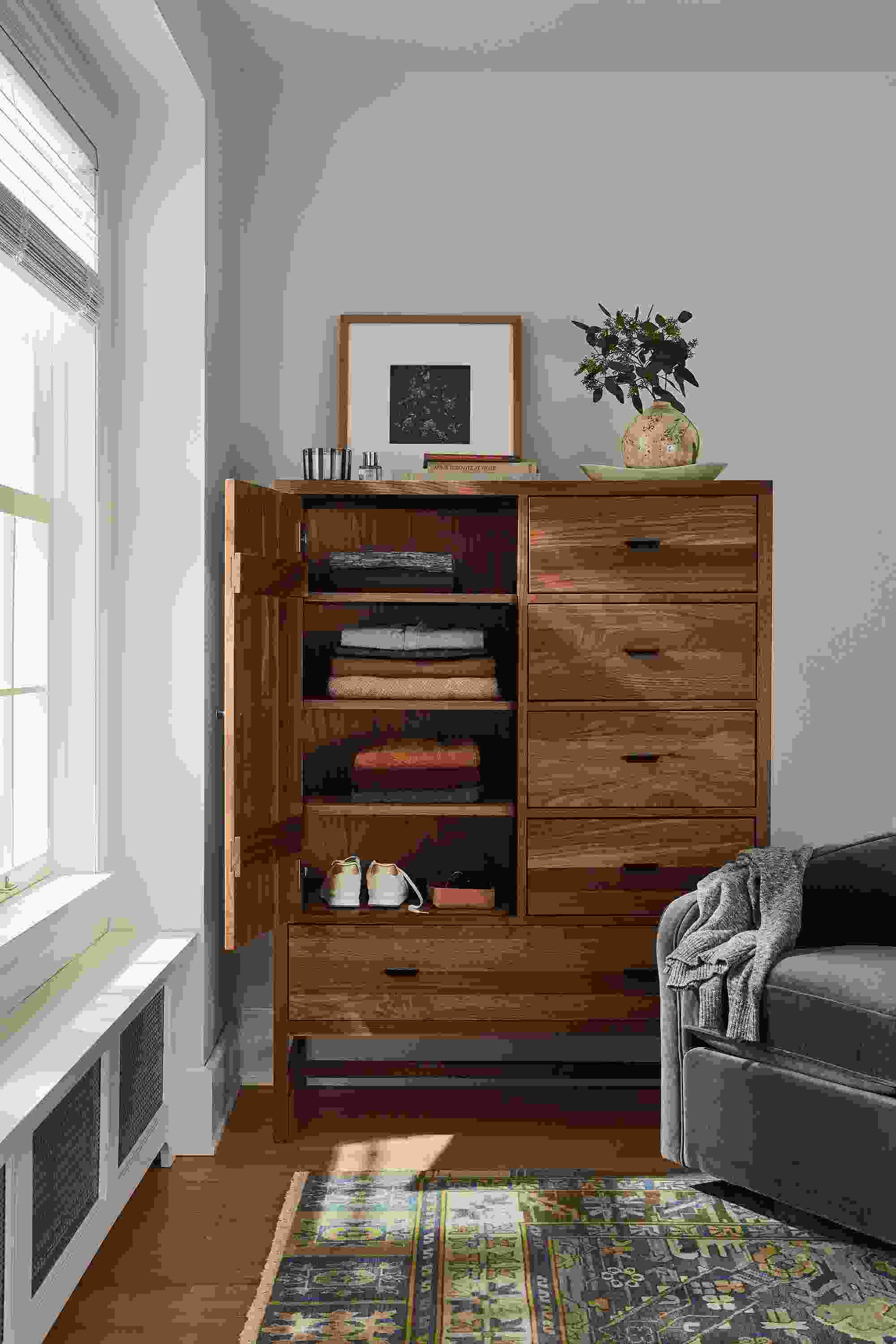 detail of berkeley storage cabinet in walnut with door open in bedroom.