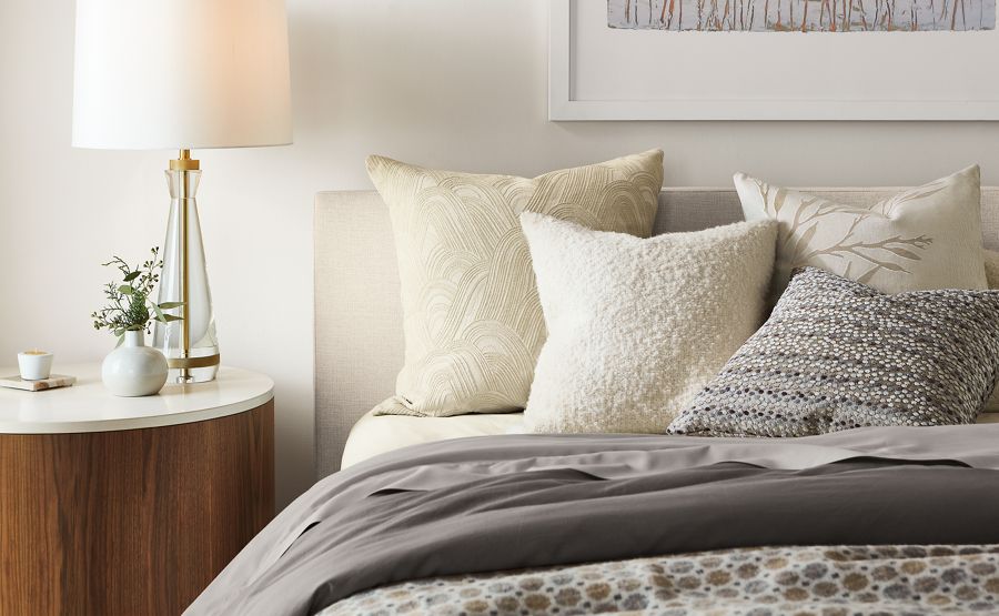 detail of white, beige and gray pillows on Wyatt bed beside Liam end table.