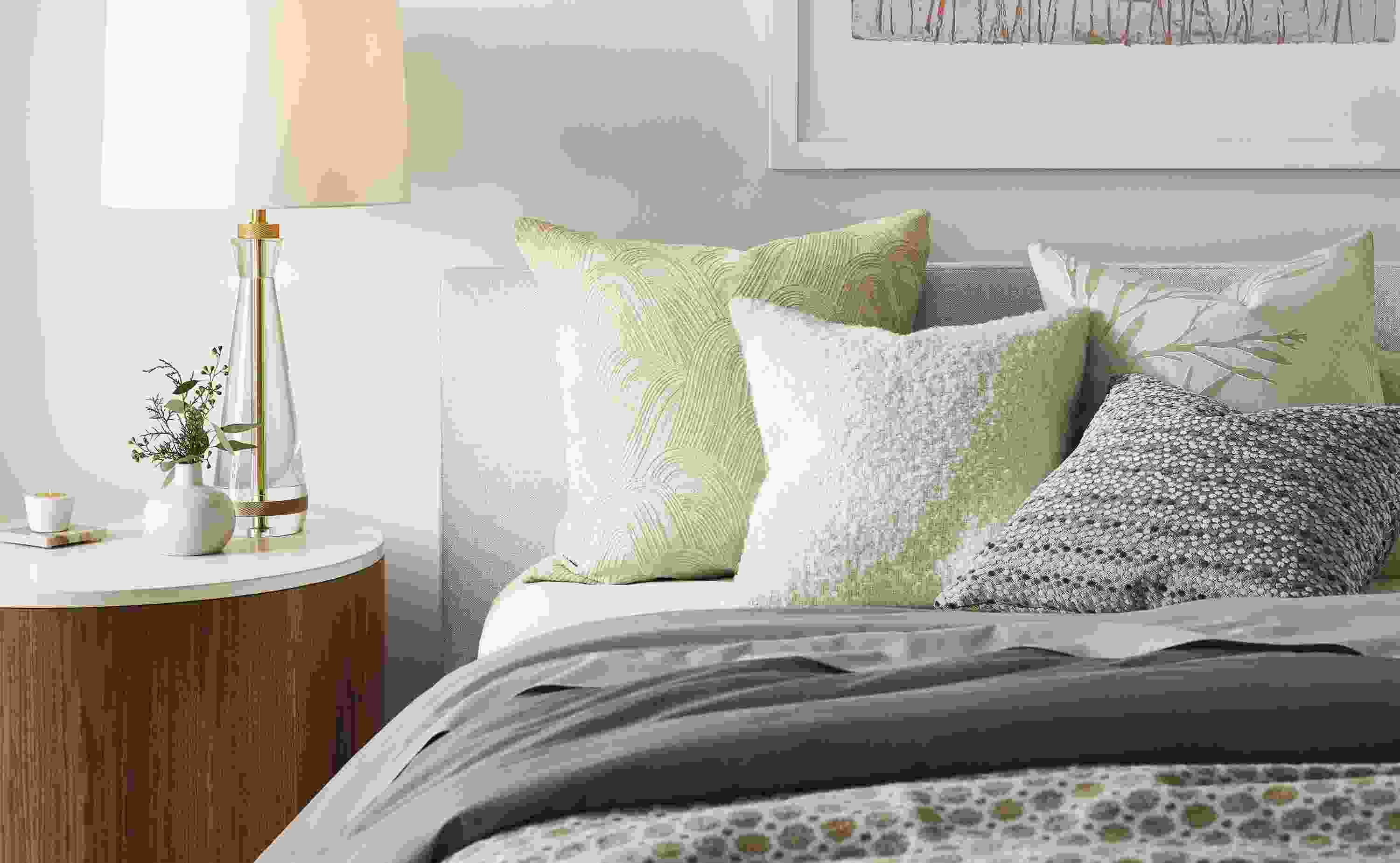detail of white, beige and gray pillows on Wyatt bed beside Liam end table.