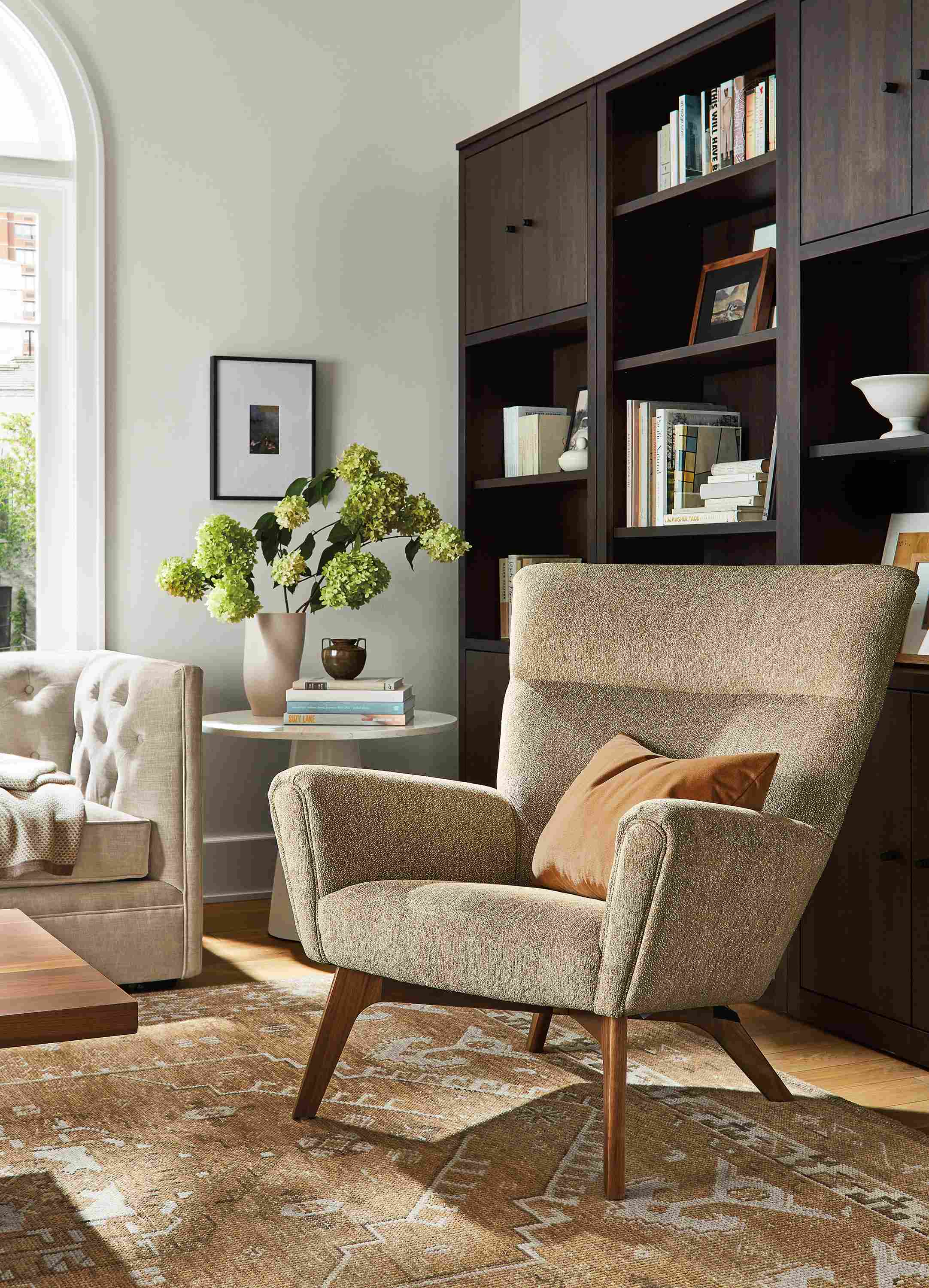 living room with boden chair in britten fabric, charcoal woodwind bookcases, darrah rug.
