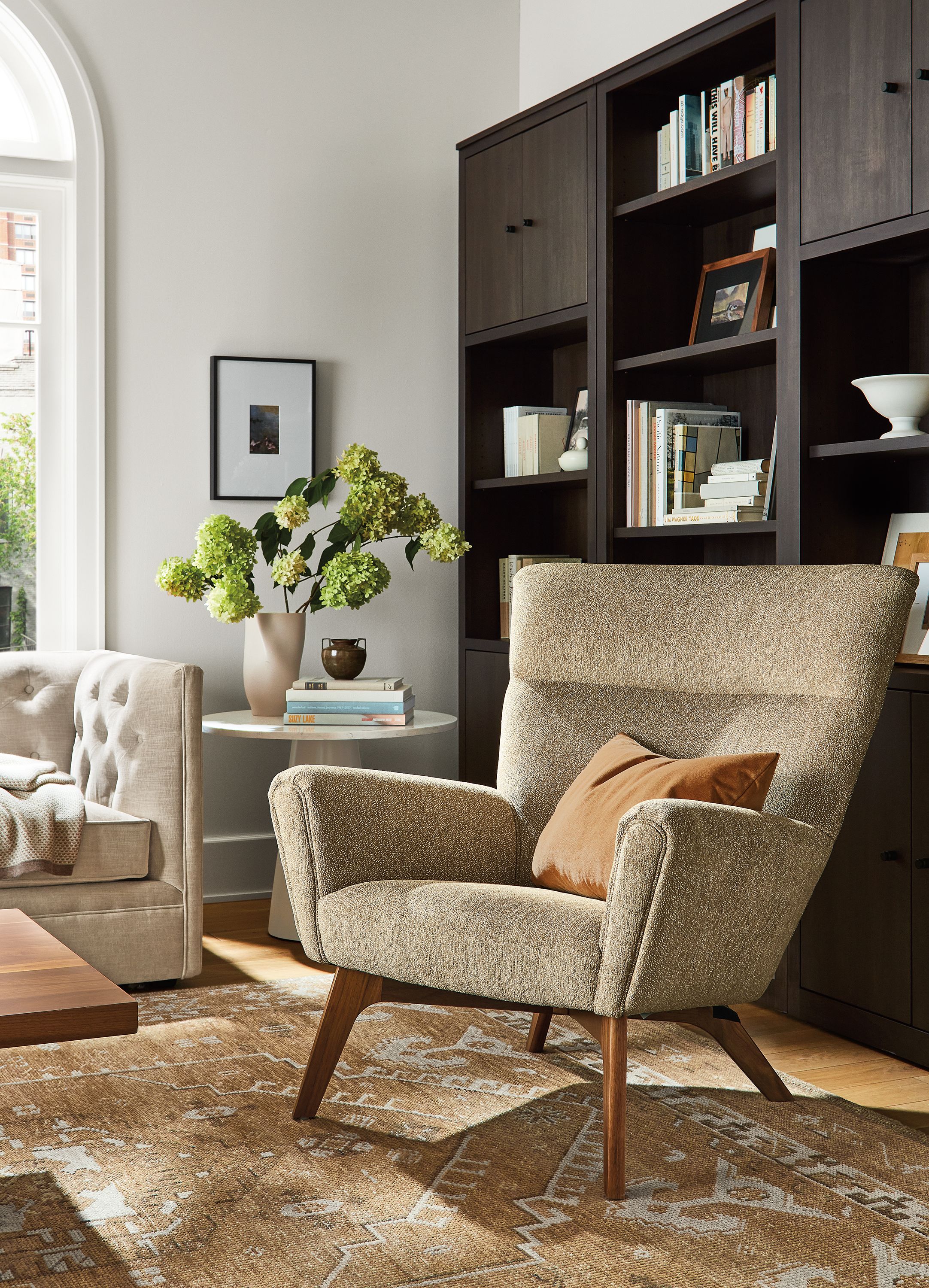 living room with boden chair in britten fabric, charcoal woodwind bookcases, darrah rug.