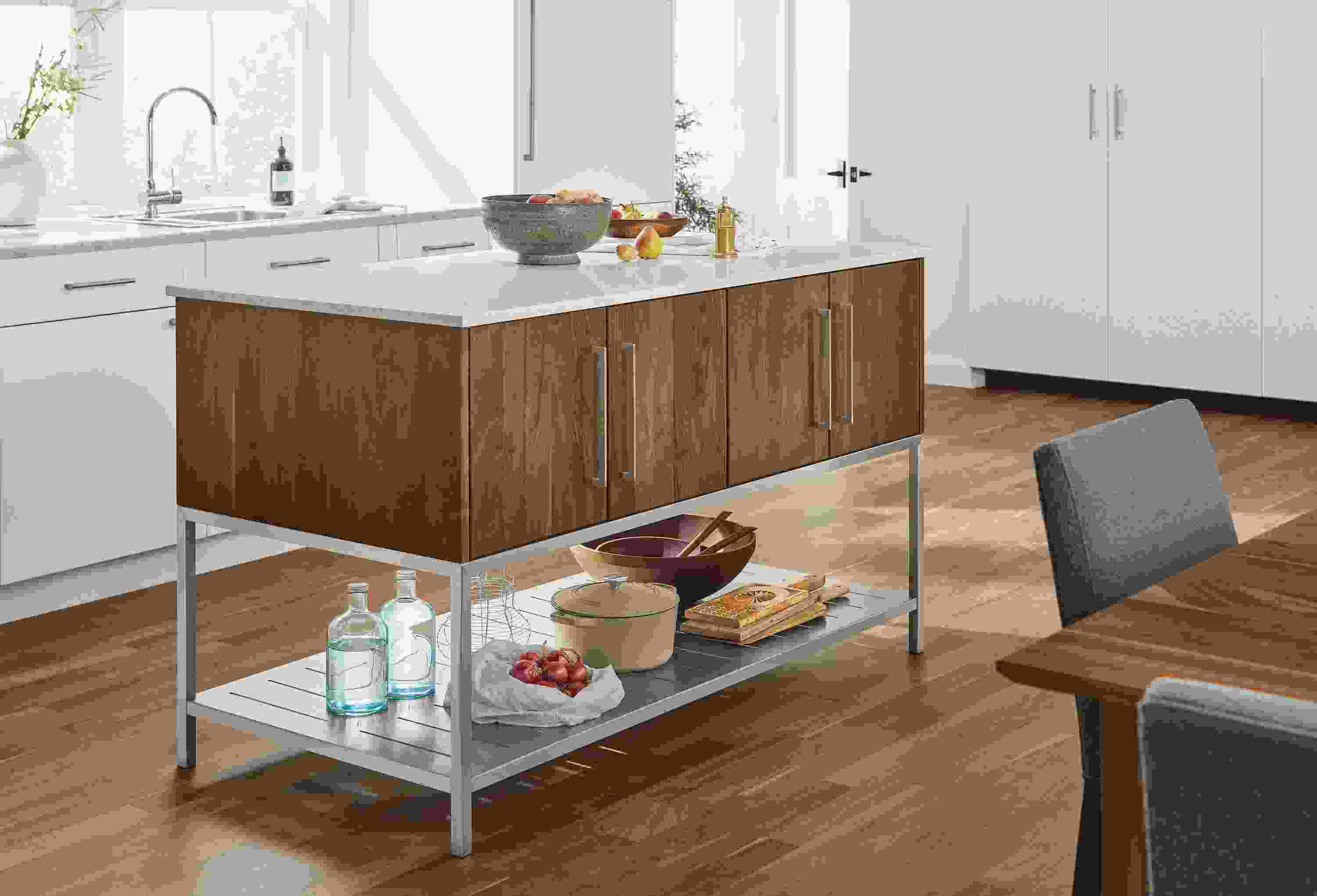 Detail of Booker kitchen island in walnut and stainless steel with marbled white quartz top in kitchen.