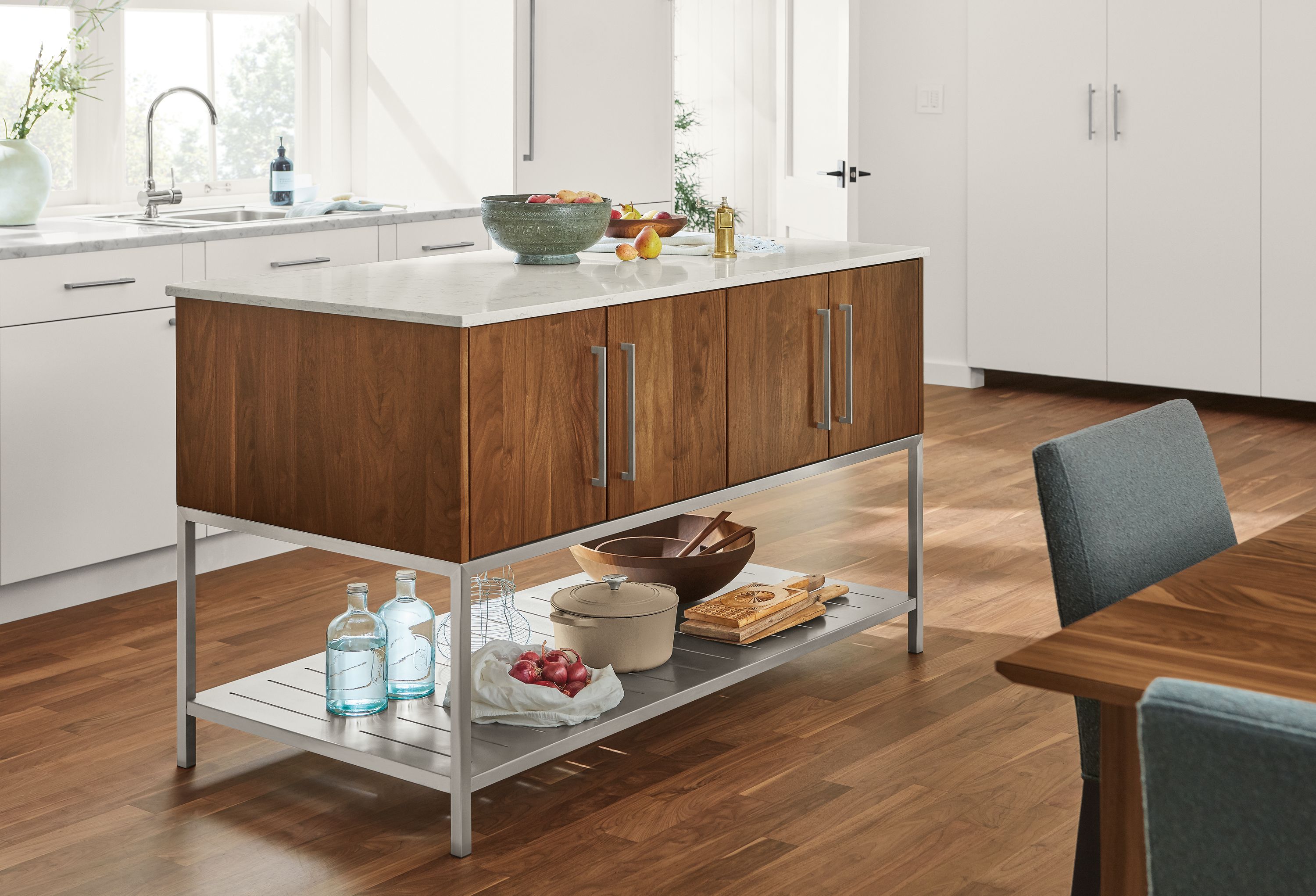 Detail of Booker kitchen island in walnut and stainless steel with marbled white quartz top in kitchen.