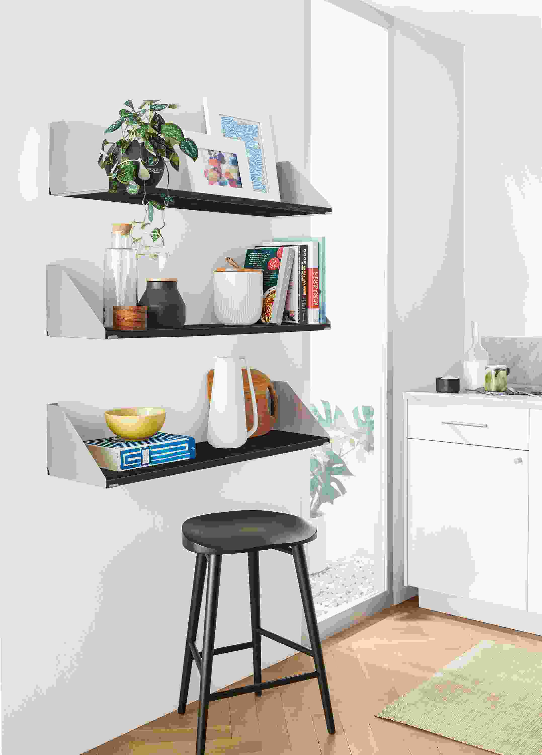 three bradley wall shelves in stainless steel holding frames, books and kitchen objects.