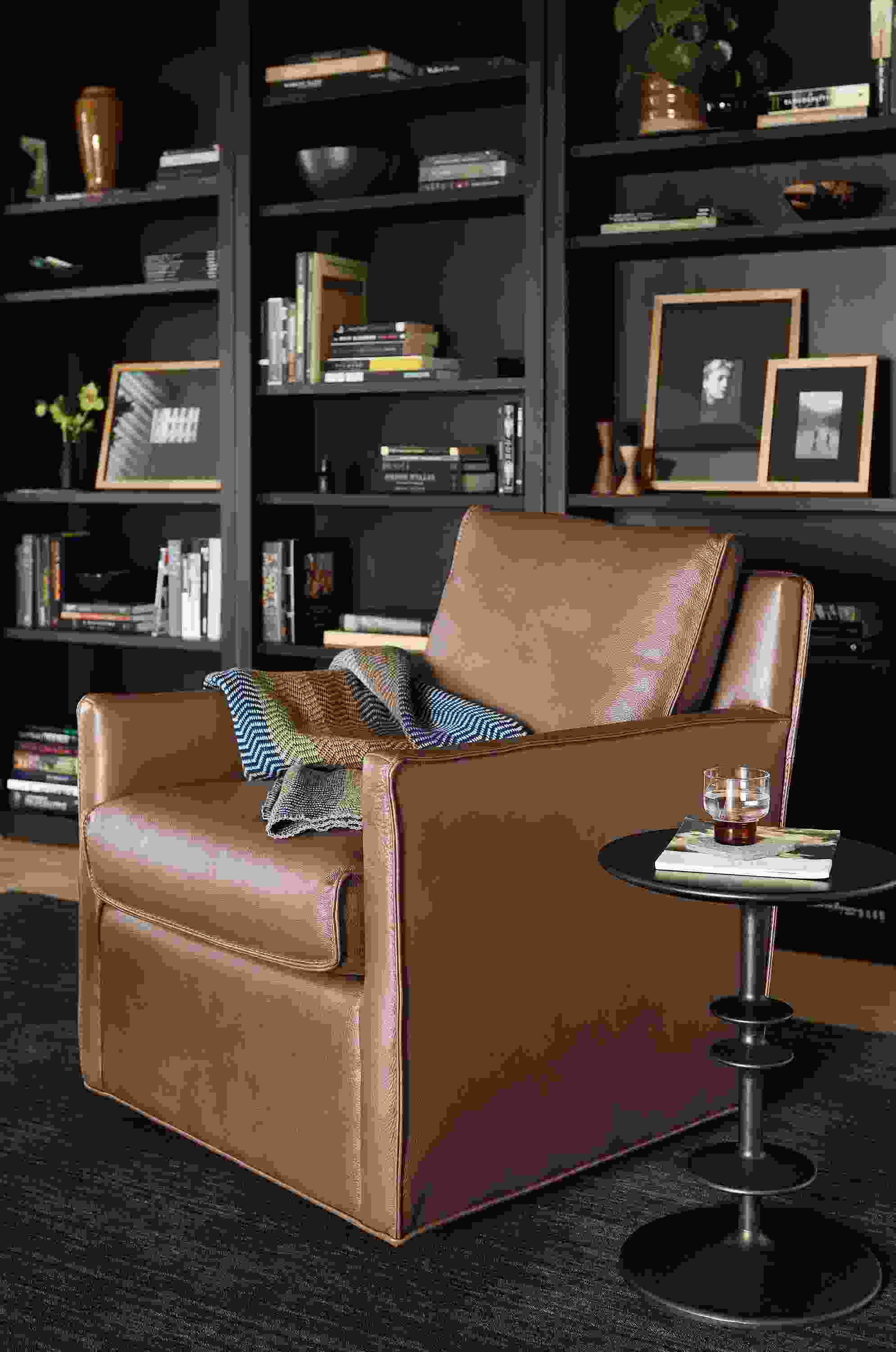 Living room with Bram swivel chair in laino cognac leather, Parks end table, woodwind bookcases in charcoal.