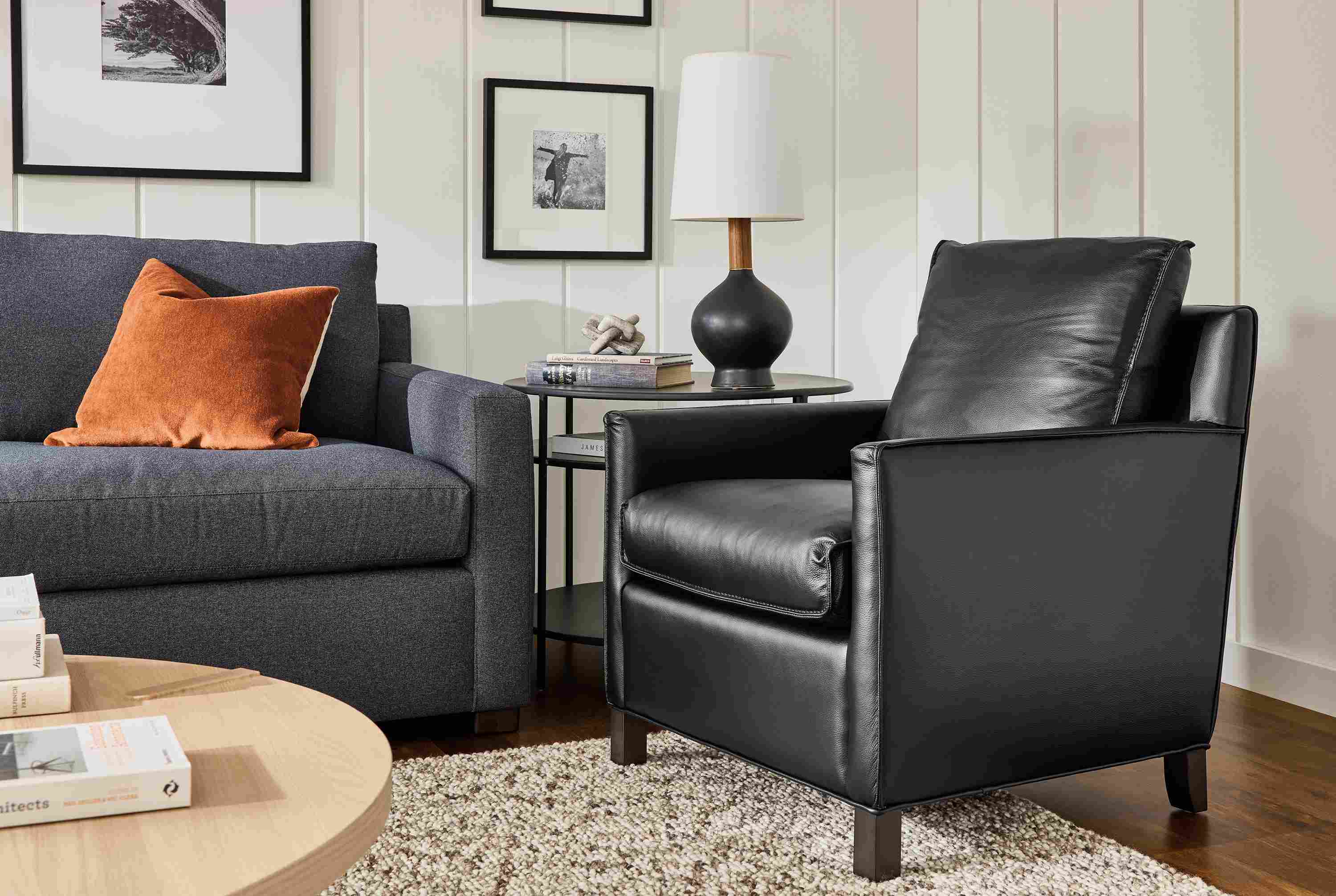 Living room with Bram chair in Pesaro Black leather, Ryan sofa in Myers Navy and Hastings loop rug in Earth.