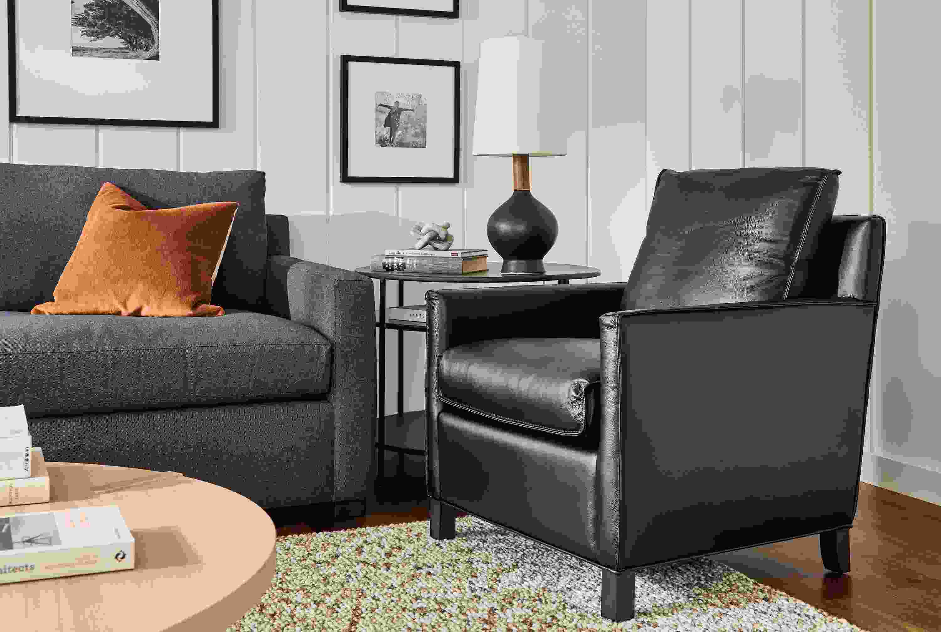 Living room with Bram chair in Pesaro Black leather, Ryan sofa in Myers Navy and Hastings loop rug in Earth.