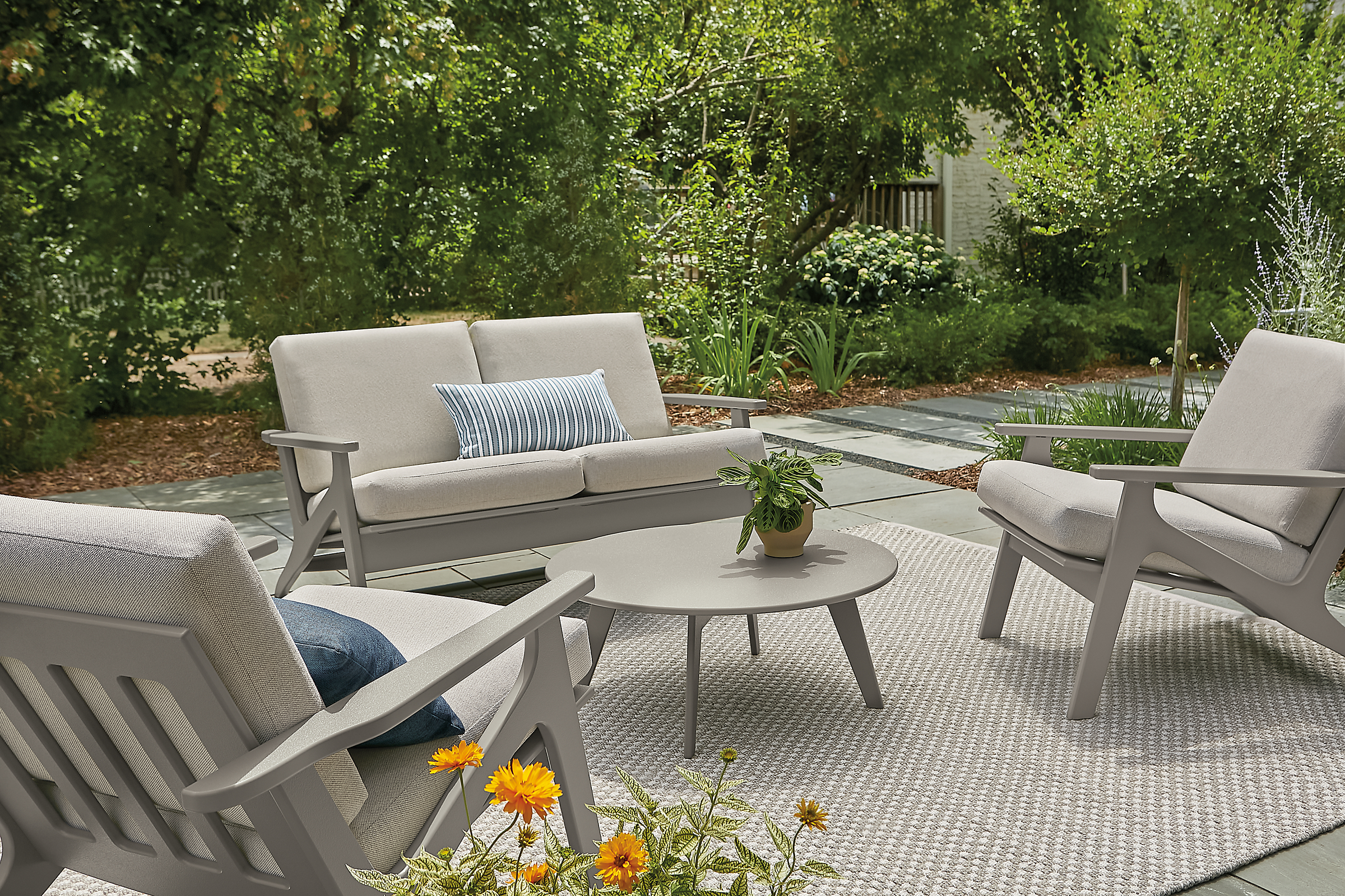 outdoor space with two breeze chairs, a breeze sofa and a nova coffee table in putty colorway.