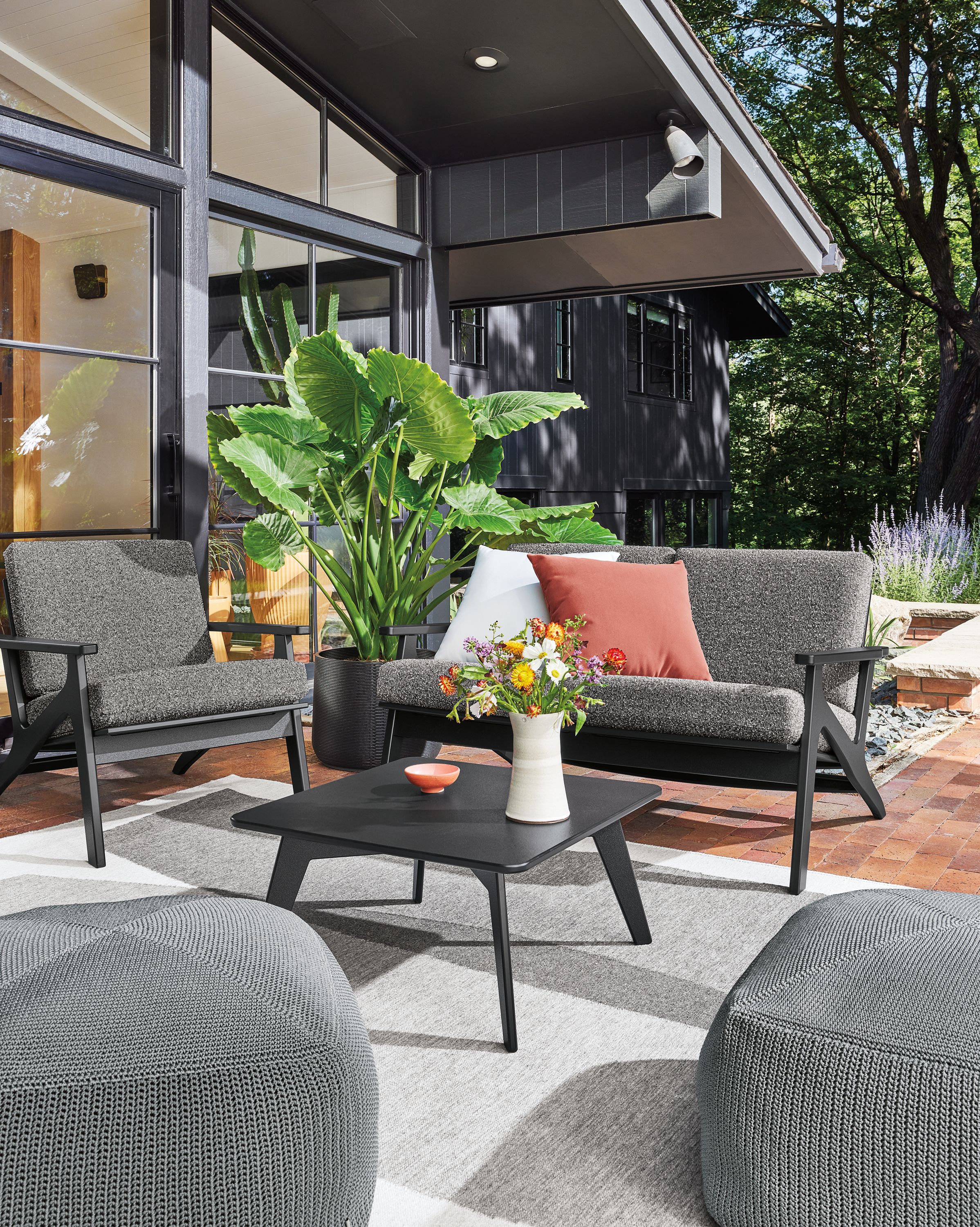 Breeze outdoor sofa and chair in black with kloss charcoal cushions, nova table and zena poufs in grey.