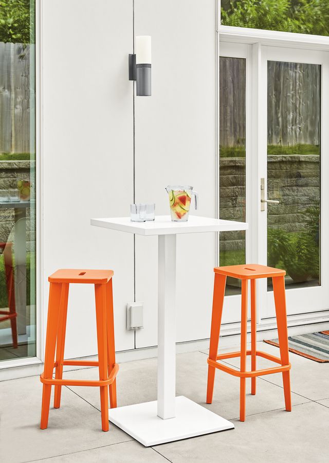 Detail of two Brook bar stools in orange on patio.