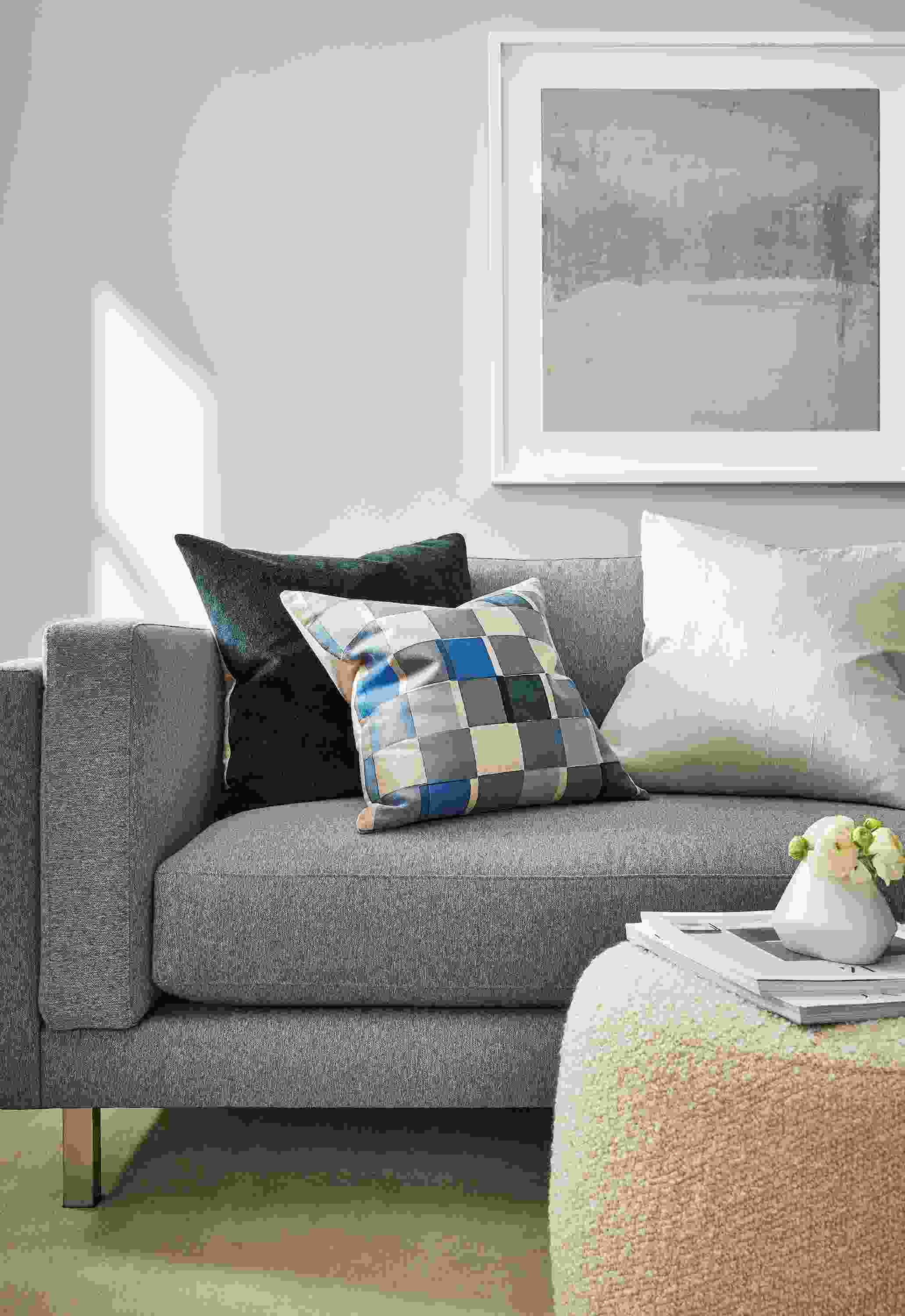 Living room with Cade sofa in Flint Grey, Lind 42-diameter ottoman in Dornick Ivory and various throw pillows.