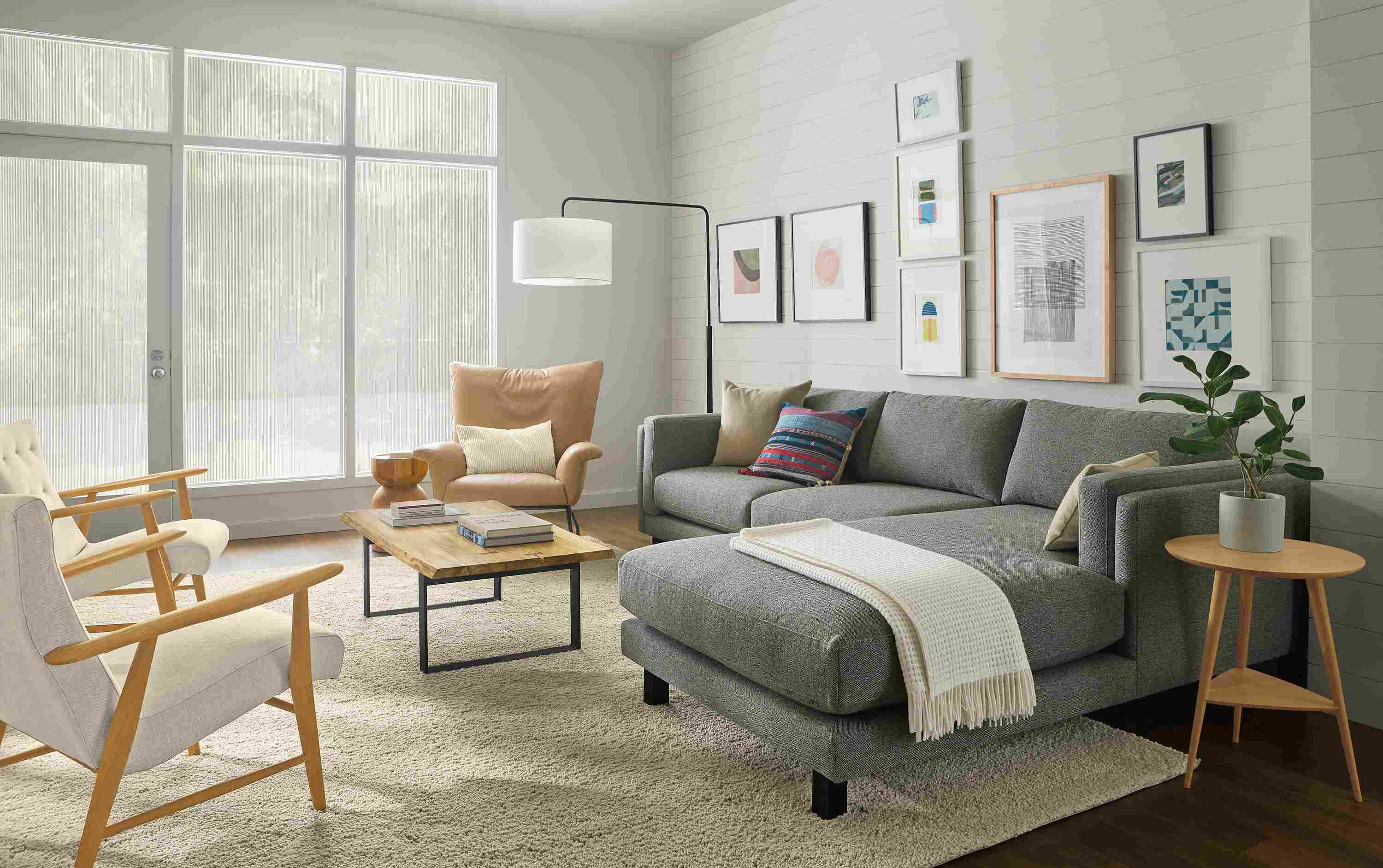 Living room with cade 114-wide sofa with right-arm chaise in tatum slate, paris chair in fiero camel leather and Arden rug in oatmeal.