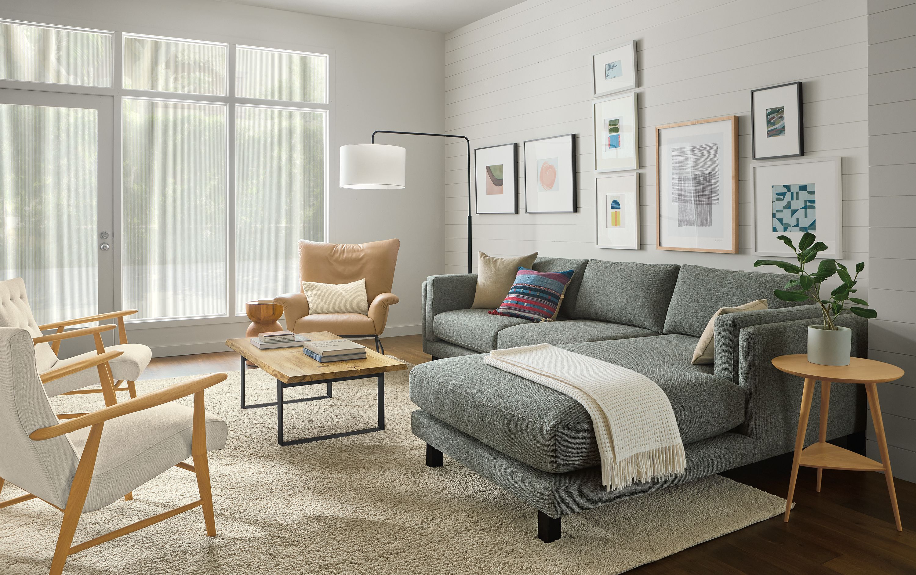 Living room with cade 114-wide sofa with right-arm chaise in tatum slate, paris chair in fiero camel leather and Arden rug in oatmeal.