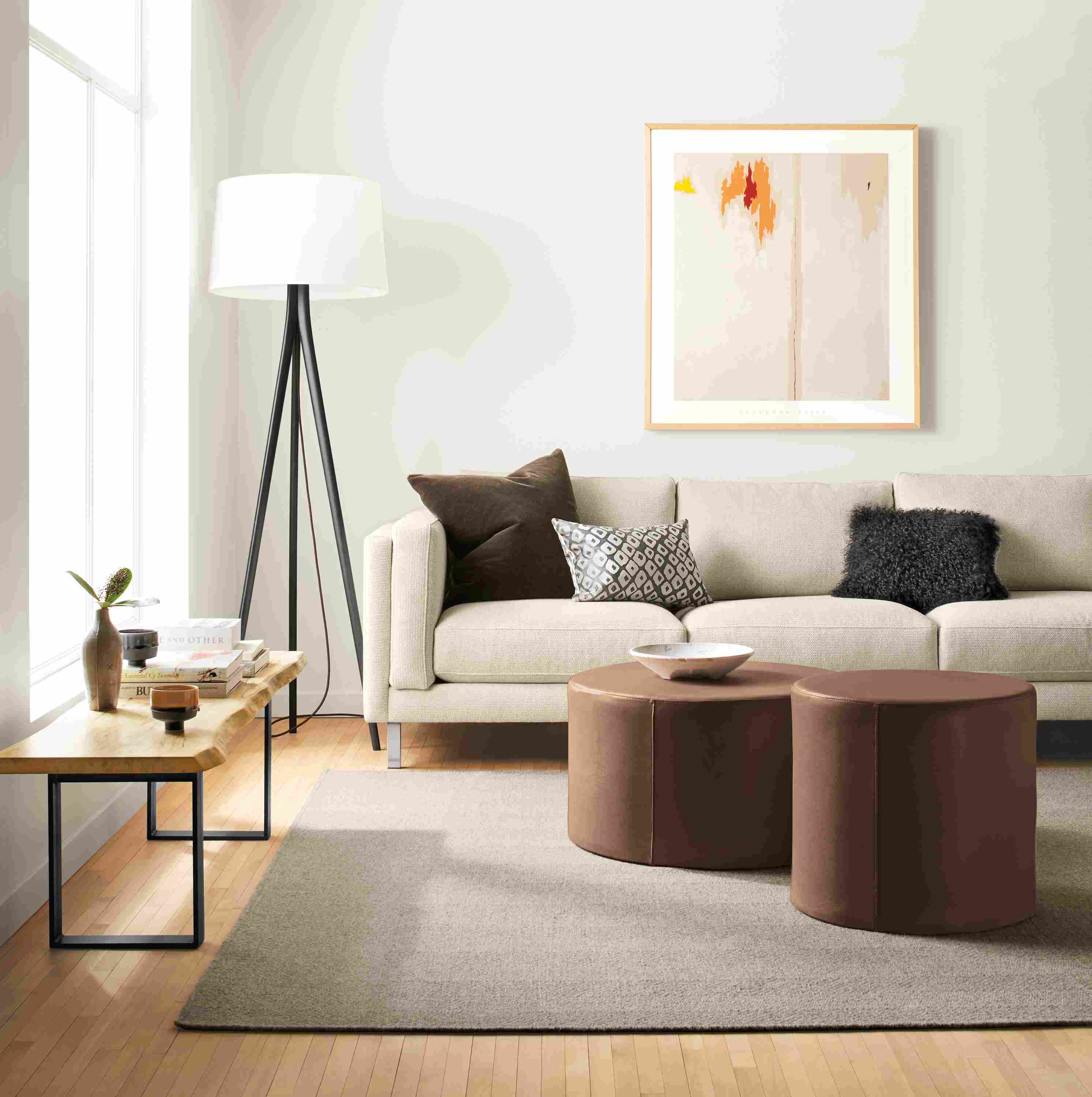 Living room with Cade sofa in orla ivory, 2 aero round ottomans in laino cognac leather and avilia rug in taupe.