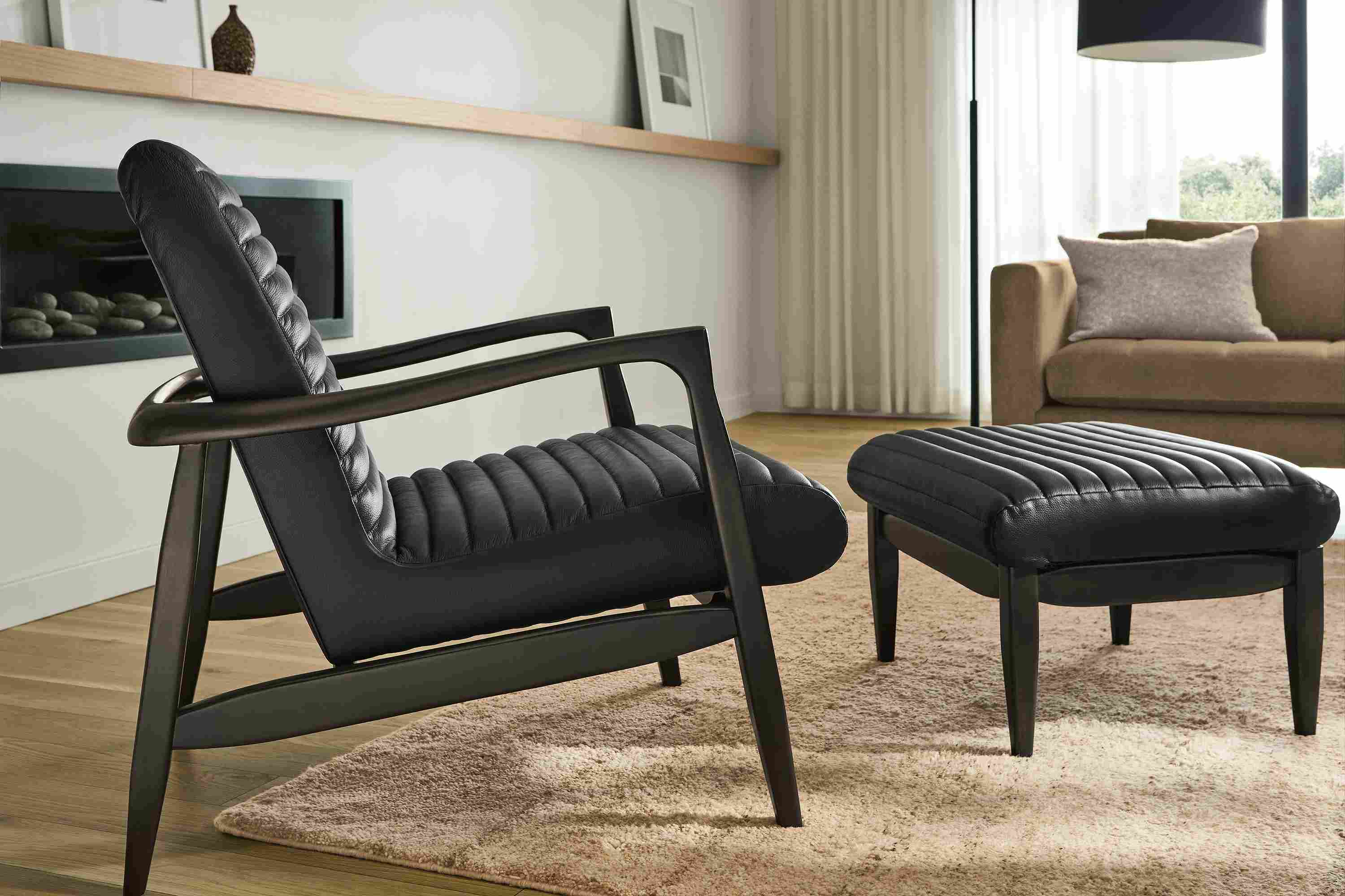 Living room with detail of Callan chair and ottoman in Pesaro Black leather and charcoal and Kalindi rug in flax.