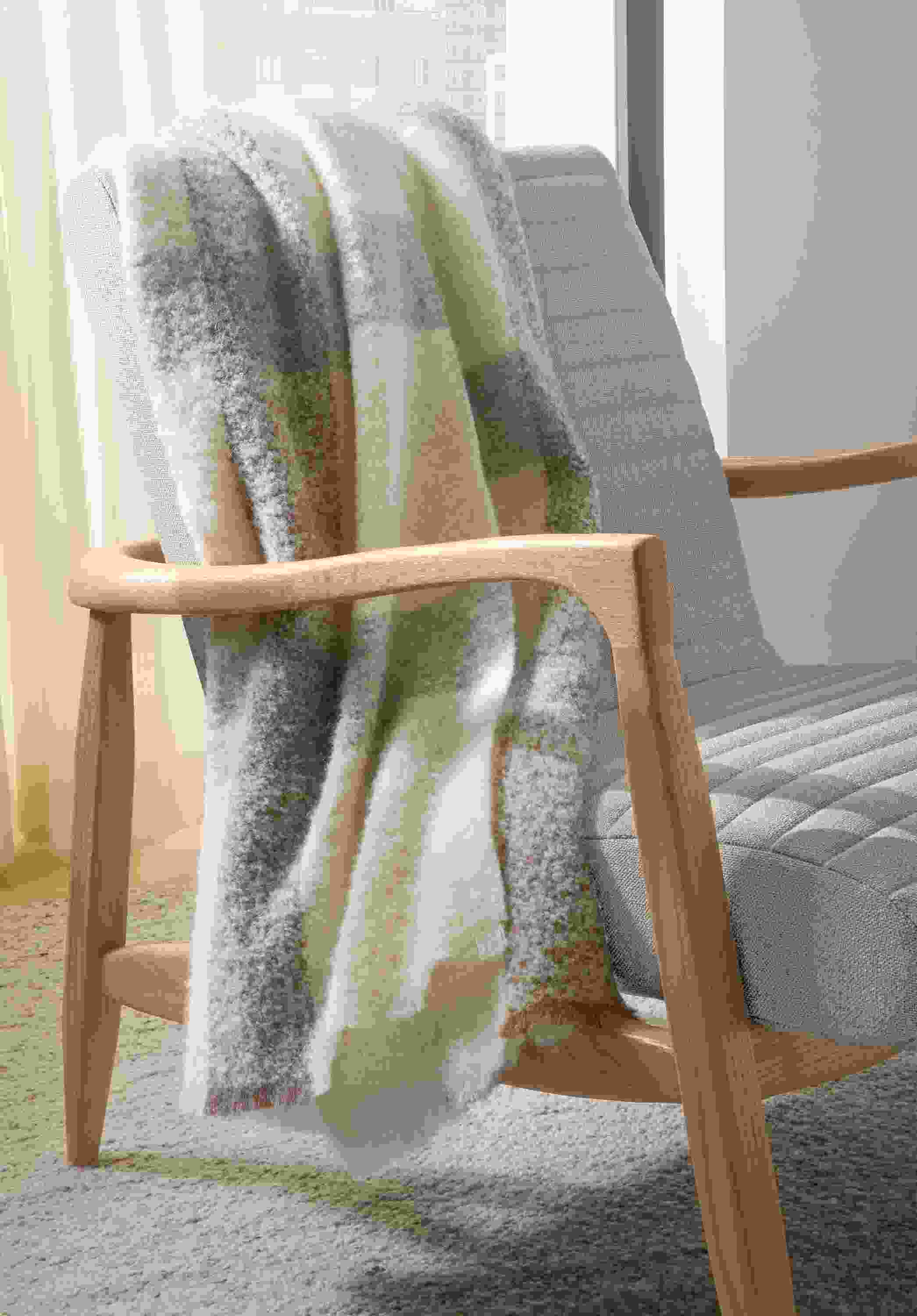 Detail of Callan chair in Landen Asphalt and rye on red oak, Sefton rug in cement and Beamont throw blanket in natural.