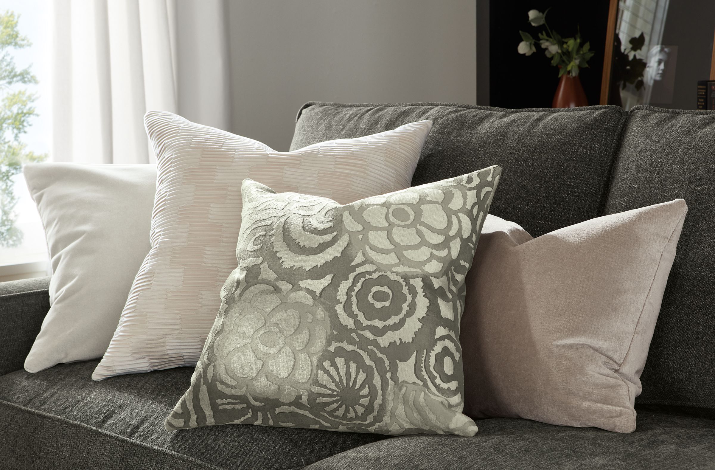 Candace, Makena and Velvet pillows stacked on gray sofa.