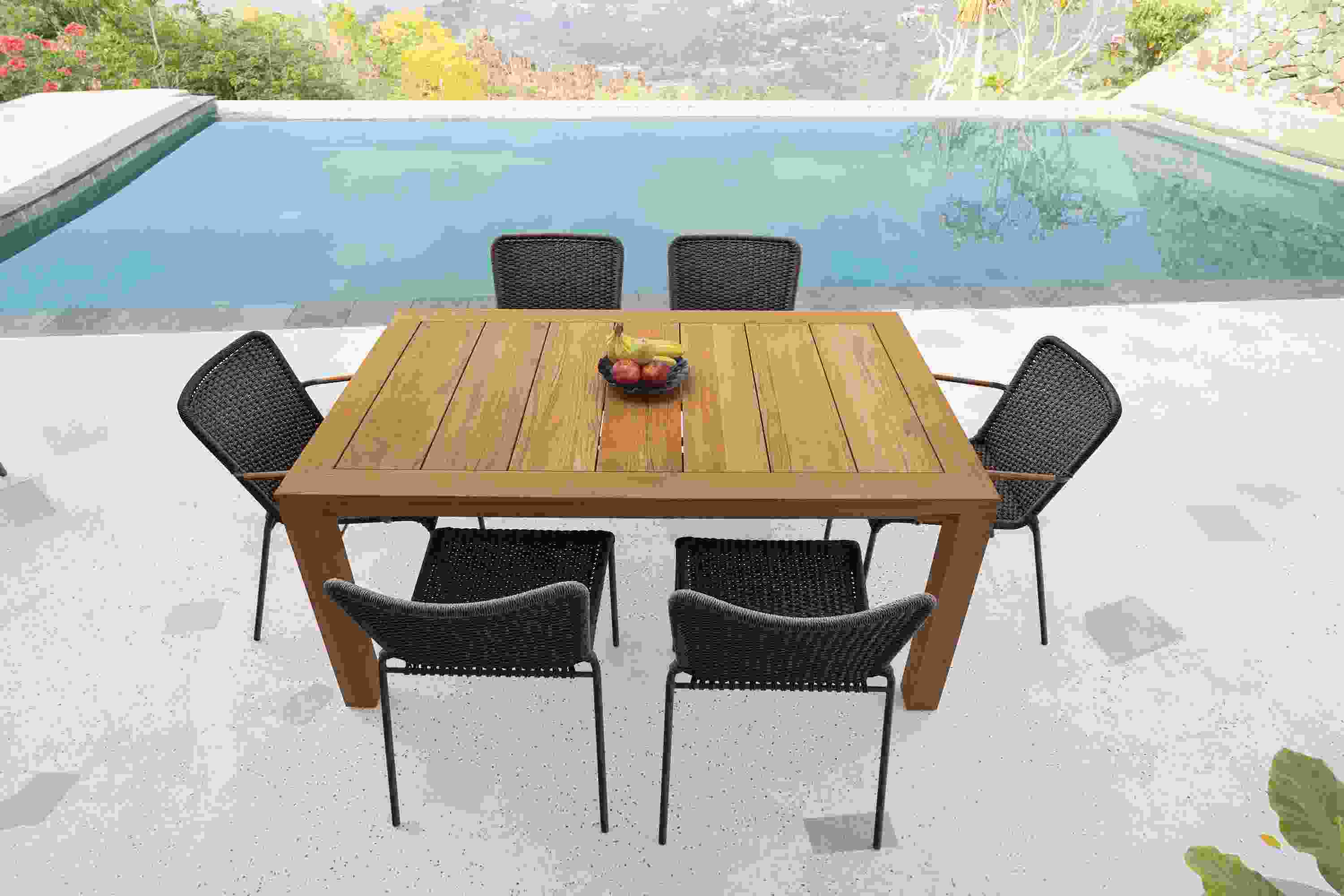 Outdoor patio with Capri 60 by 40 extension table in teak and Clea Outdoor side chairs and arm chairs in Black.
