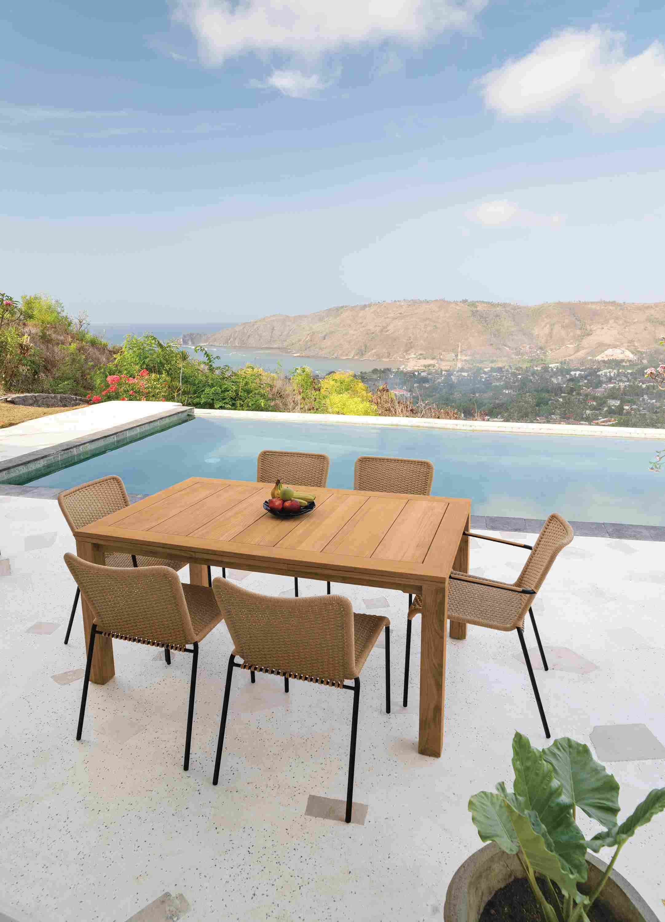 Outdoor patio with Capri 60 by 40 extension table in teak and Clea Outdoor side chairs and arm chairs in Natural cording.