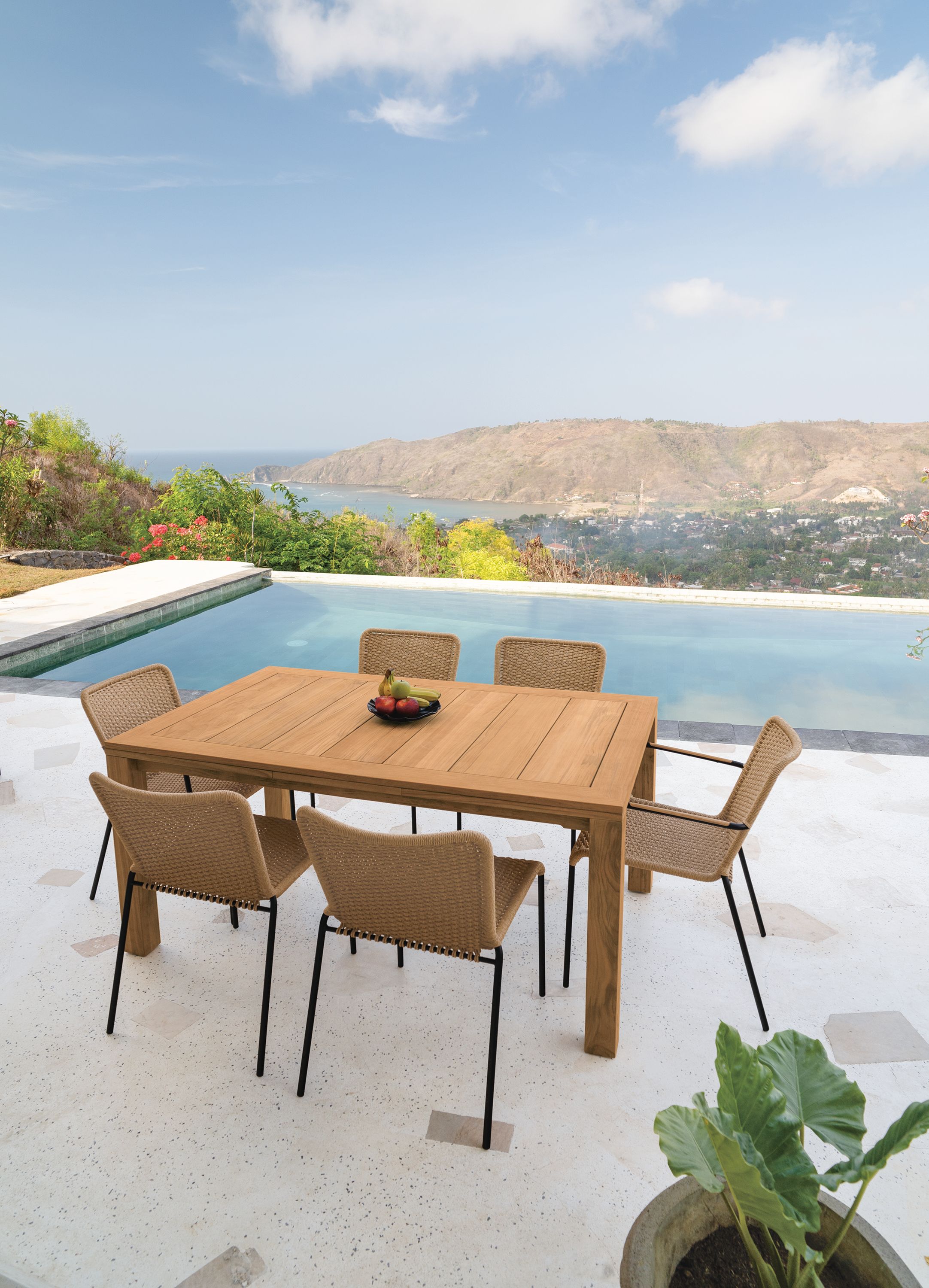 Outdoor patio with Capri 60 by 40 extension table in teak and Clea Outdoor side chairs and arm chairs in Natural cording.