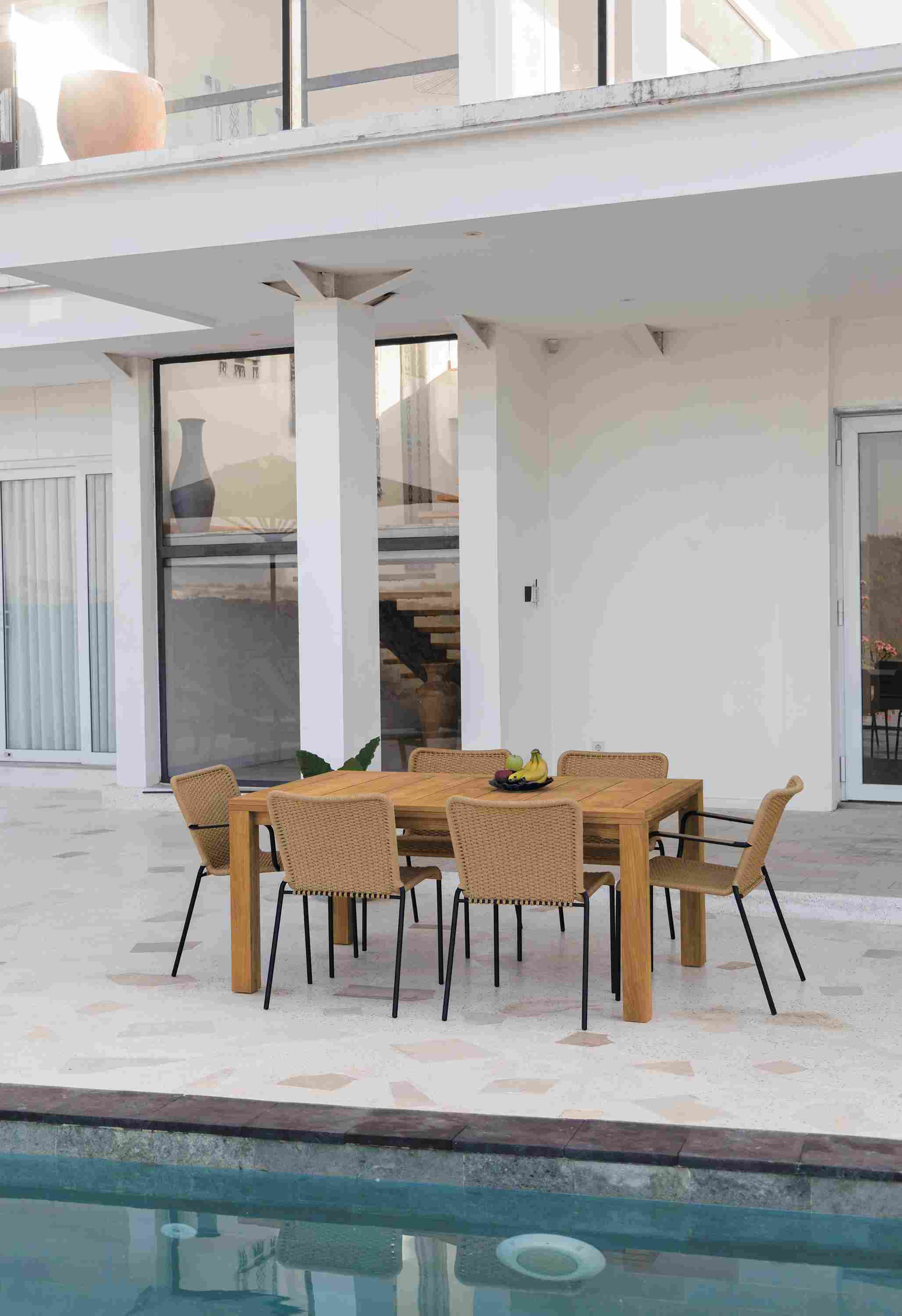 Outdoor patio with Capri 60 by 40 extension table in teak and Clea Outdoor side chairs and arm chairs in Natural.