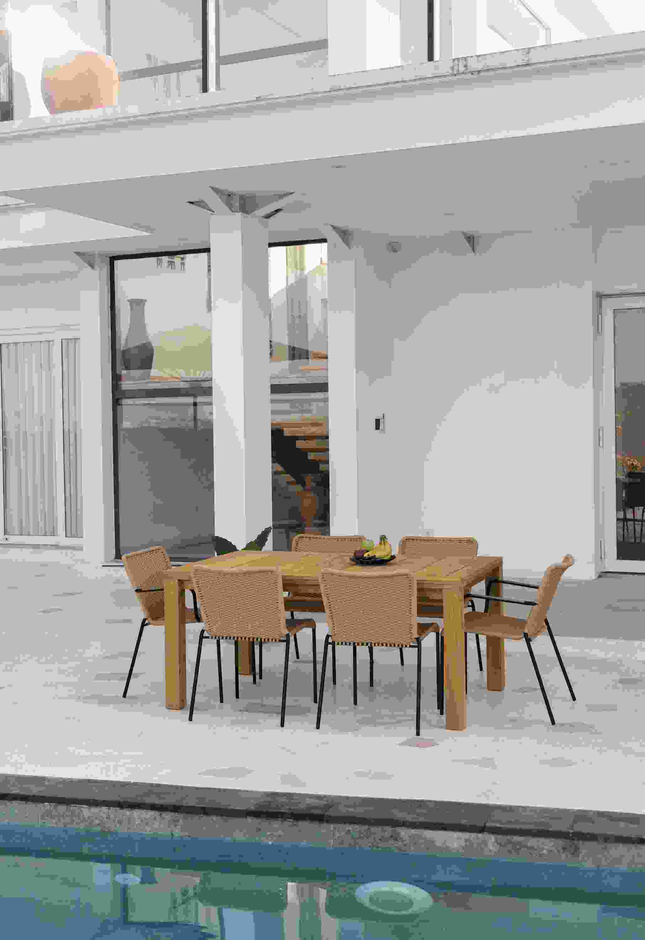 Outdoor patio with Capri 60 by 40 extension table in teak and Clea Outdoor side chairs and arm chairs in Natural.