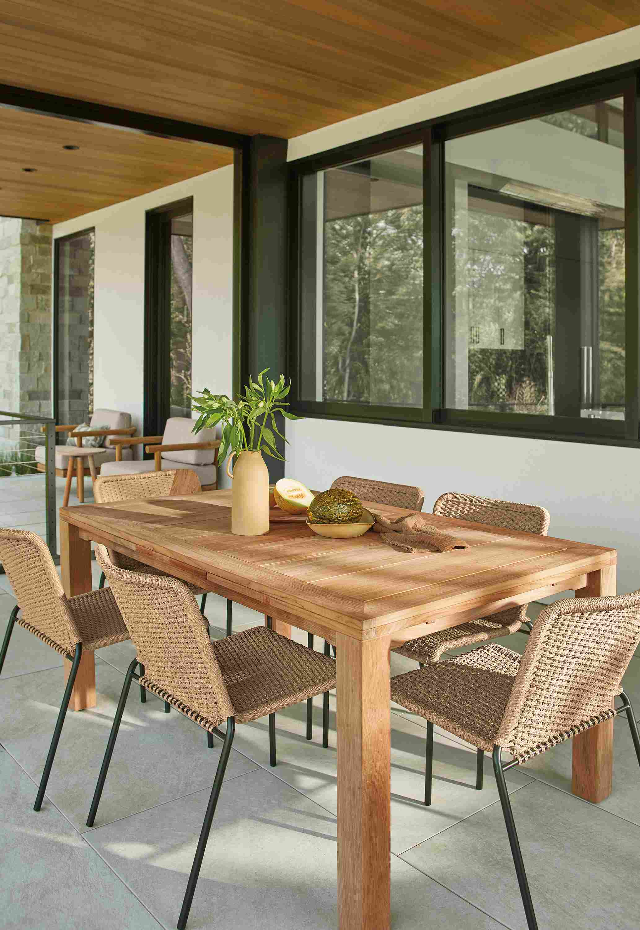 Home indoor/outdoor dining space with Capri extension tables in teak heartwood and Clea chairs in natural.