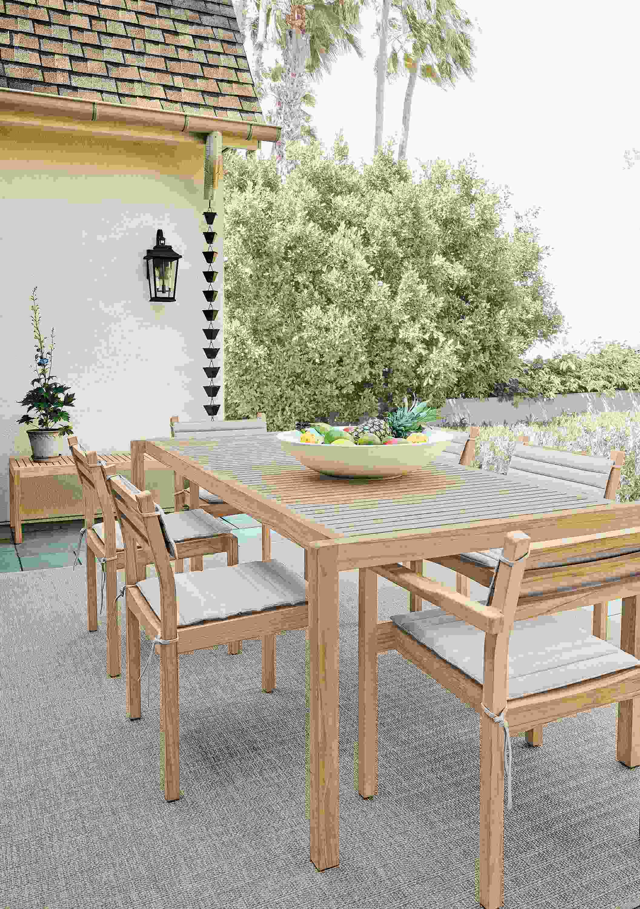 Patio with detail of carl hansen outdoor teak table, 4 outdoor side chairs and 2 outdoor arm chairs with cushions.