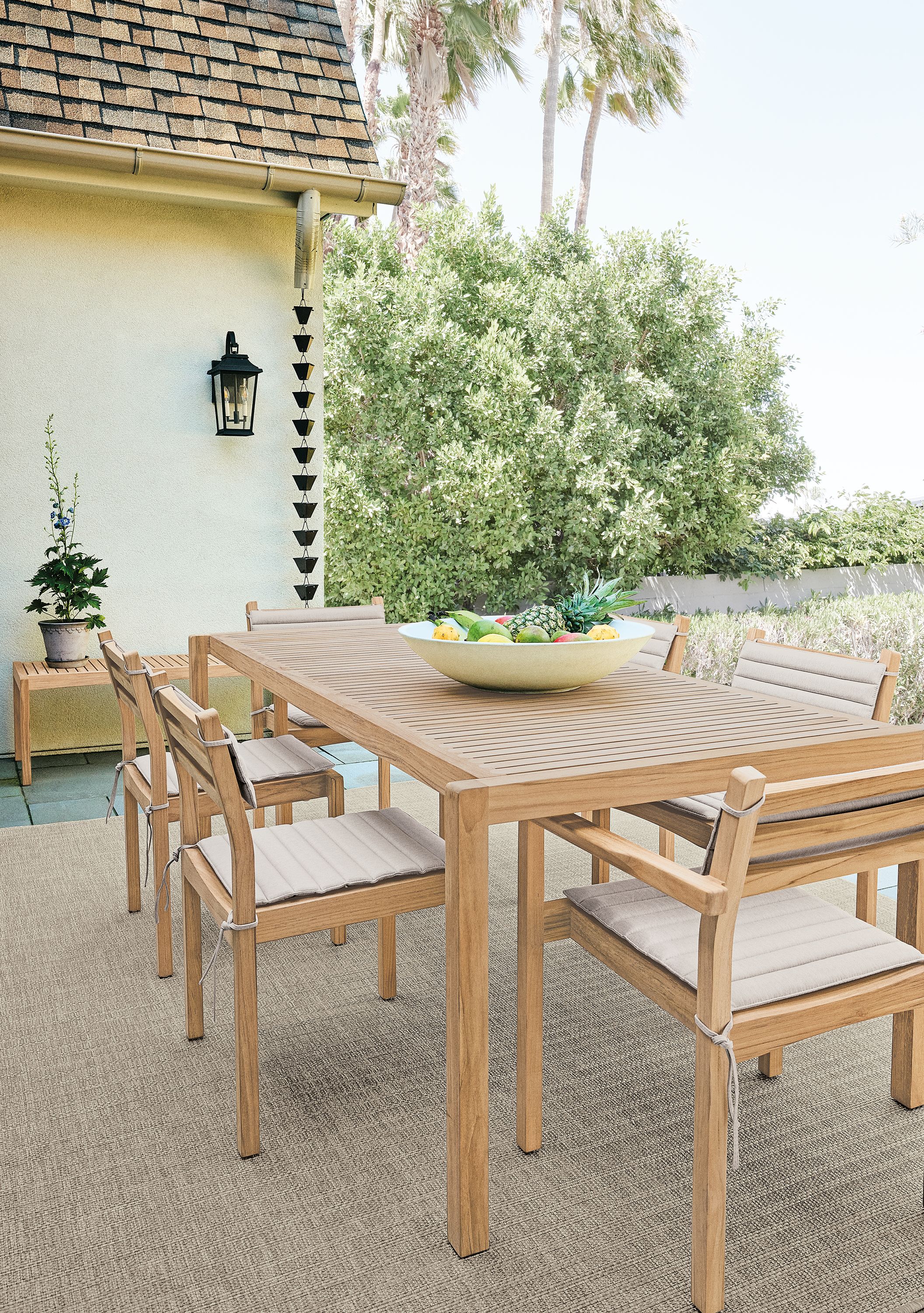 Patio with detail of carl hansen outdoor teak table, 4 outdoor side chairs and 2 outdoor arm chairs with cushions.