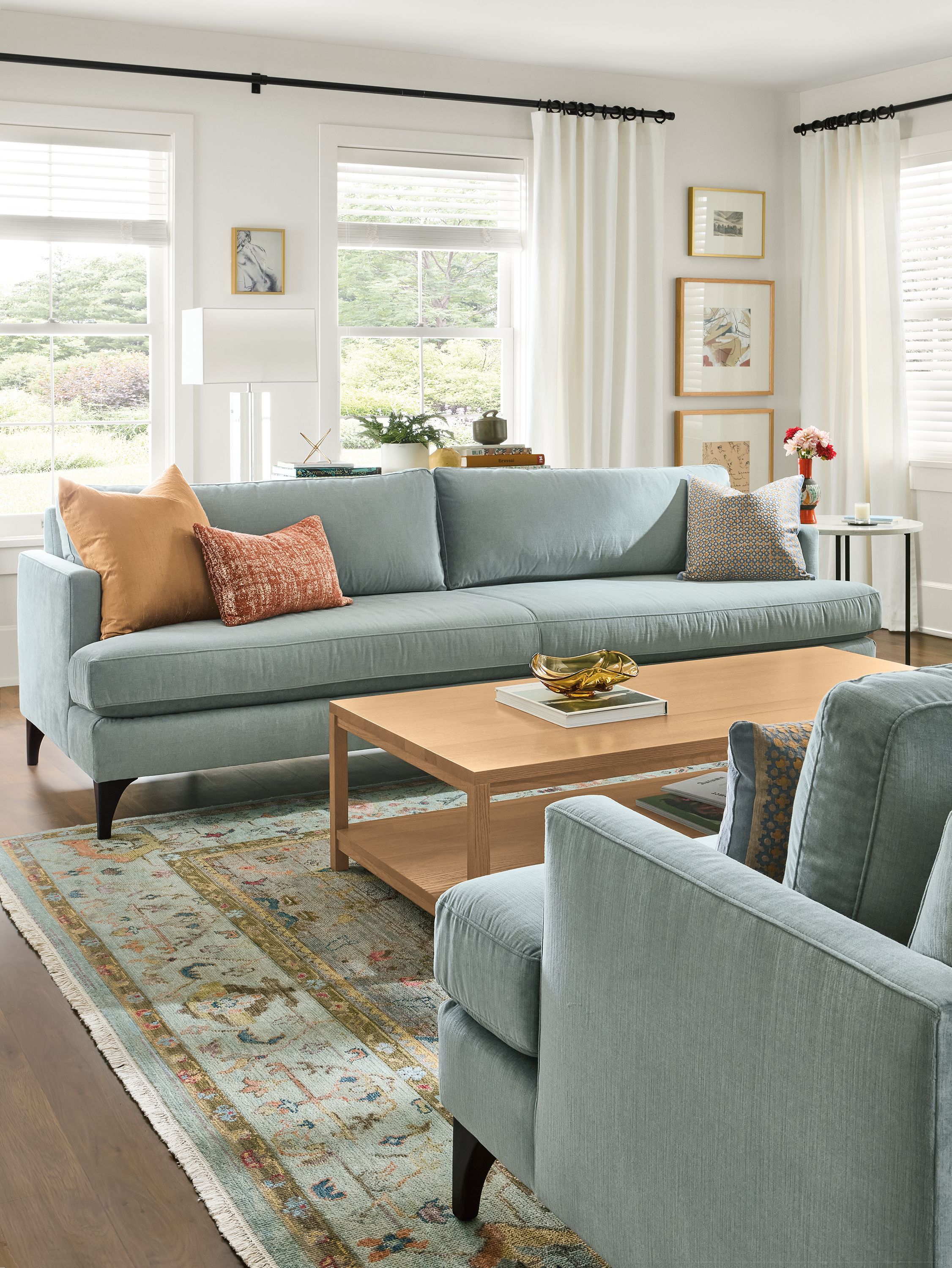 Living room with 2 carlton bench-cushion sofas in windsor cloud, clark coffee table in rye on red oak and sundar rug in sky.
