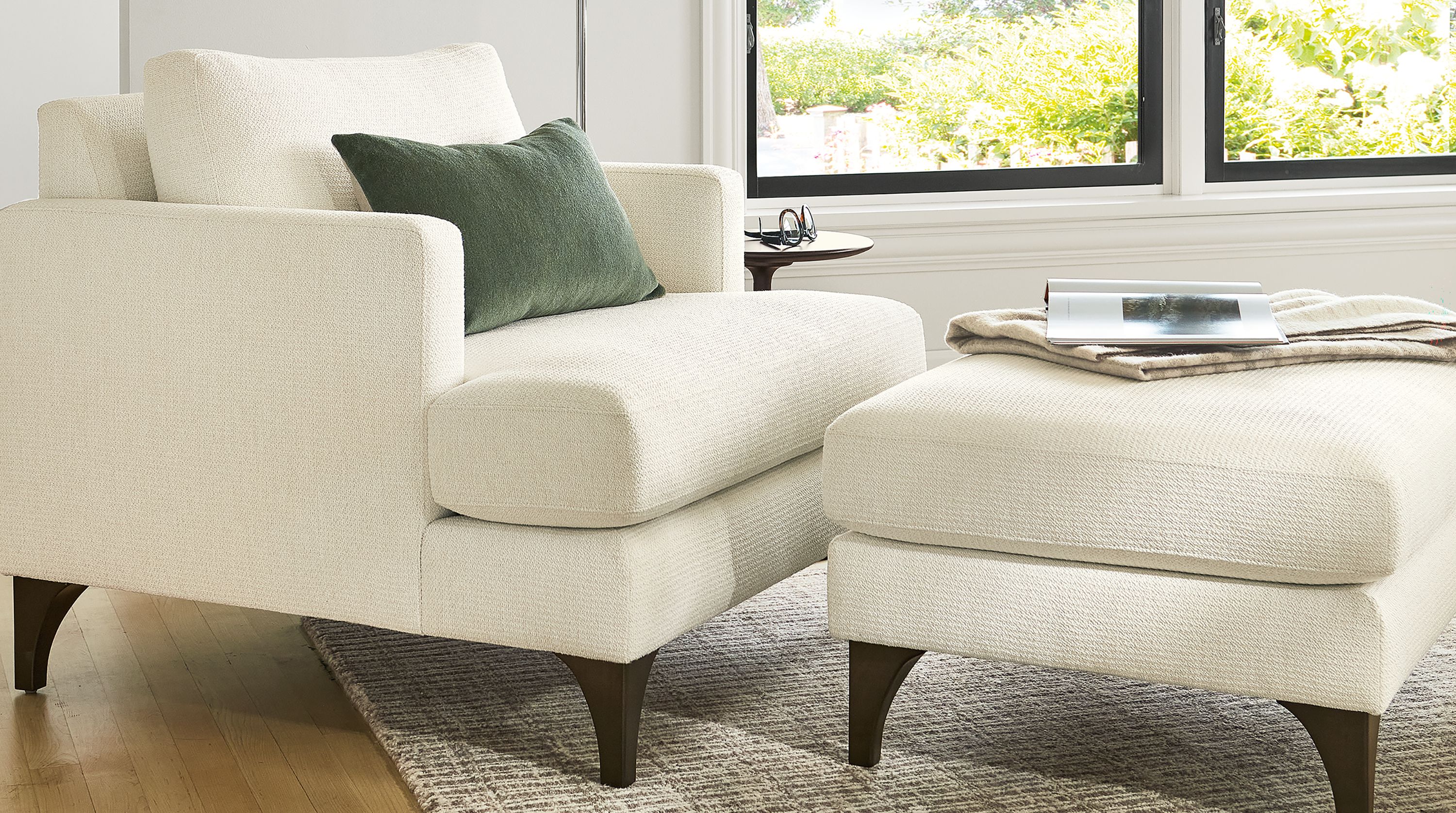 Living room with Carlton chair and ottoman in Orla White, Cohen floor lamp in polished nickel and Nera 8 by 10 rug in stone.