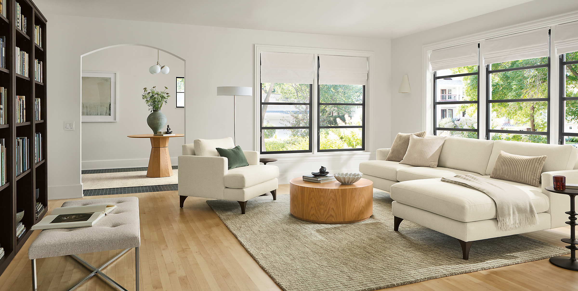 Living room with Carlton 100-wide chaise, and Carlton chair in Orla White, Liam 36 diameter coffee table in white oak.