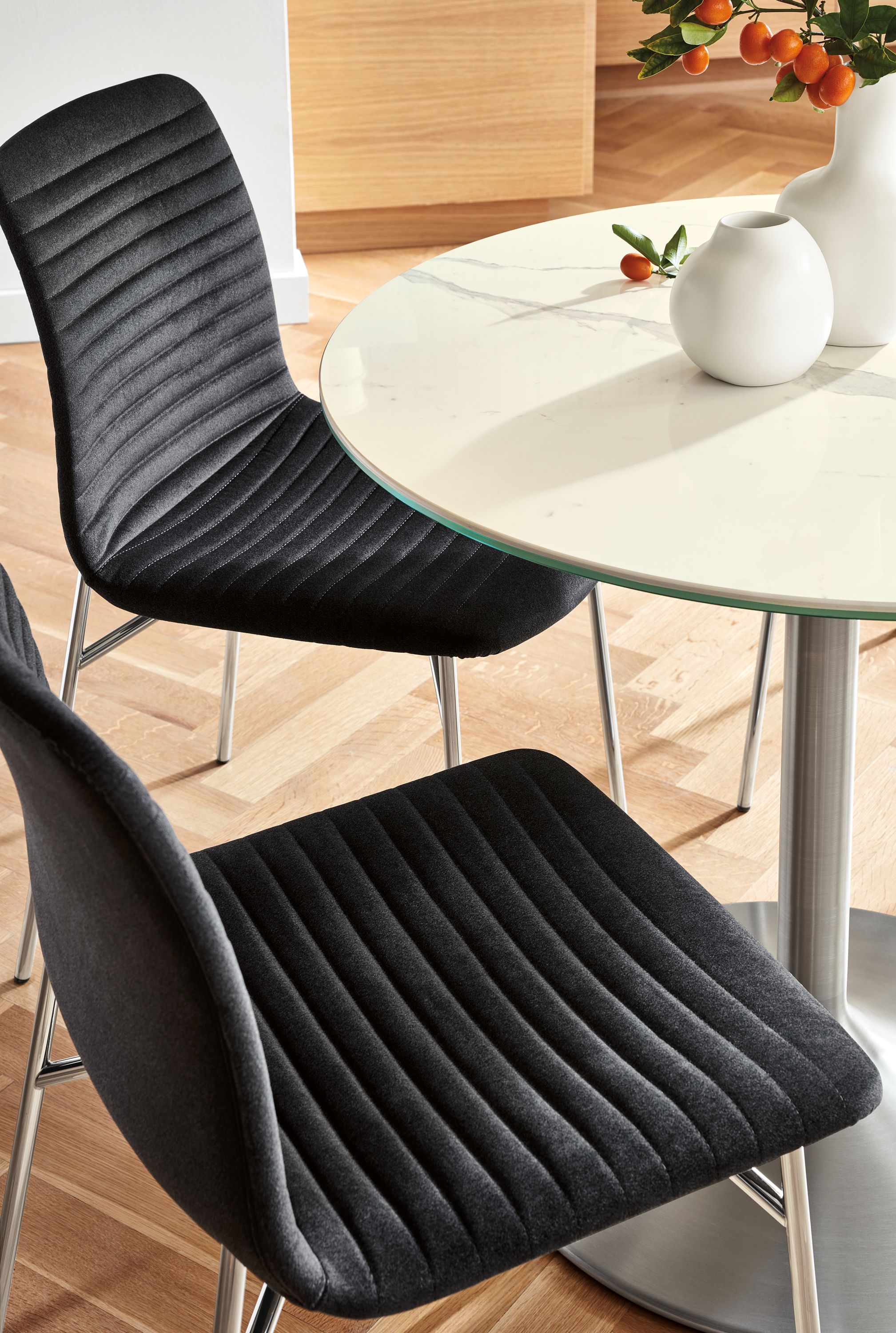 Two Cato side chairs in fabric and stainless steel Aria table.