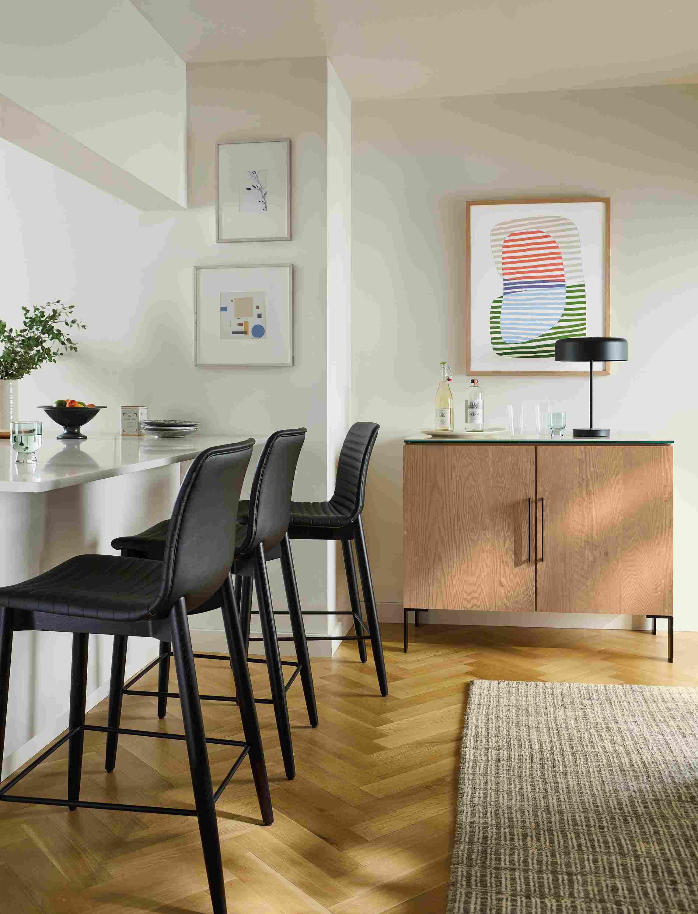 Counter seating area with 3 cato counter stools in black synthetic leather and ebony and nera rug in stone.