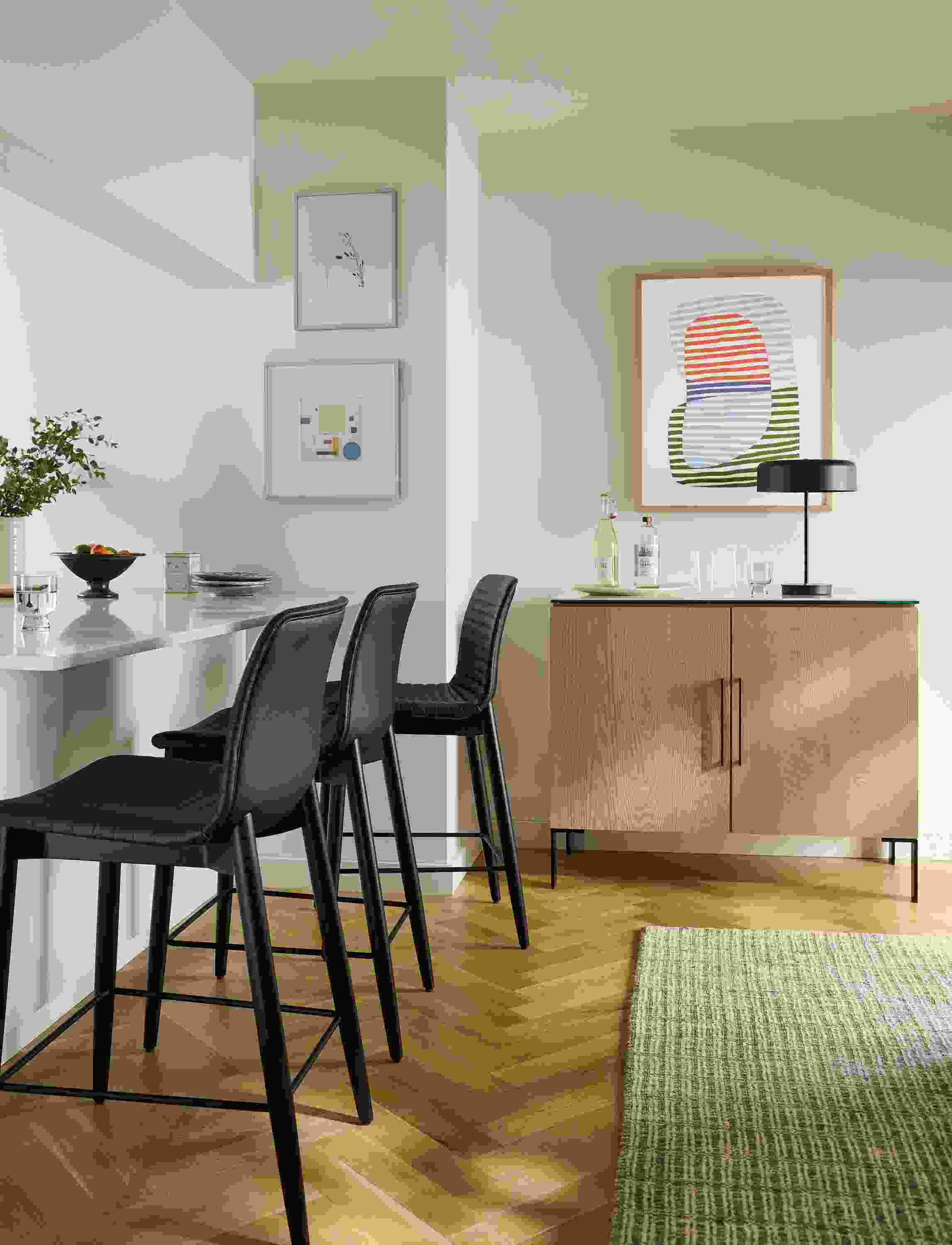 Counter seating area with 3 cato counter stools in black synthetic leather and ebony and nera rug in stone.