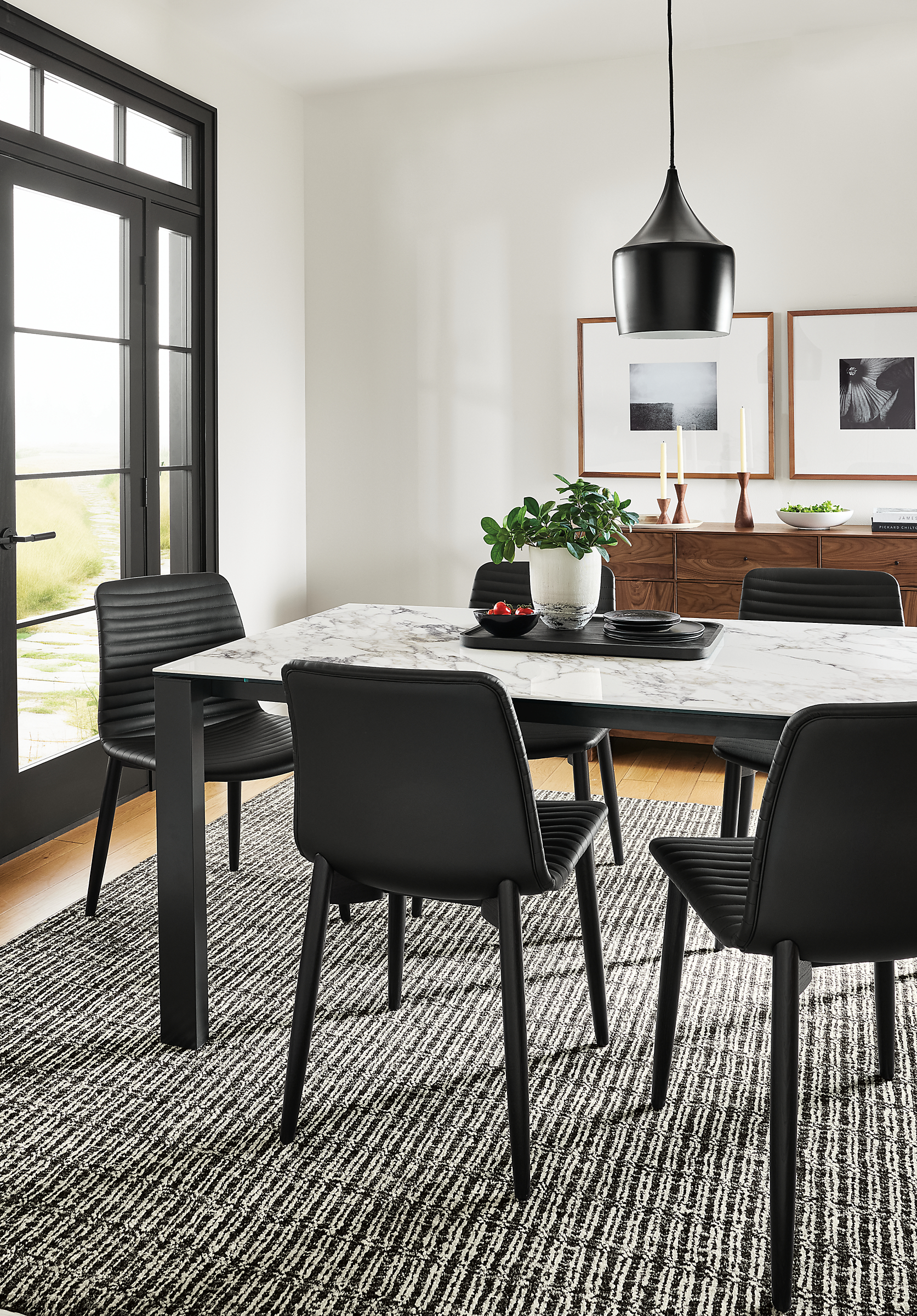 Dining room with Cato side chairs in Black Leather, Metric table with marbled bright white ceramic top and Nera rug in coal.